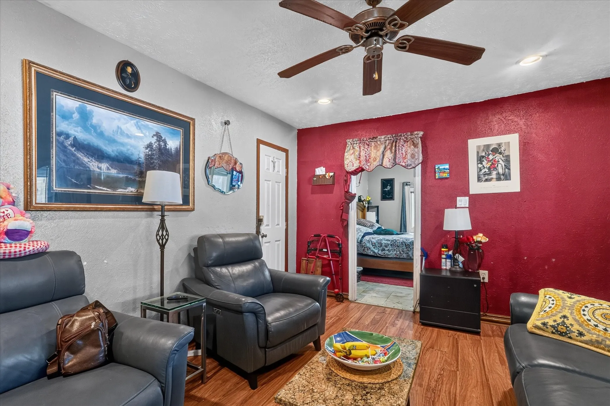 Wood-finish flooring, ceiling fan with integrated lighting, recessed ceiling lighting, textured accent wall