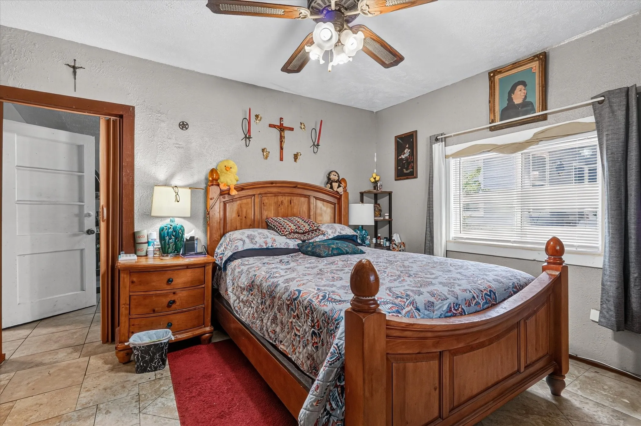 Bedroom featuring a wood-finish ceiling fan, a window with horizontal blinds, and tile flooring