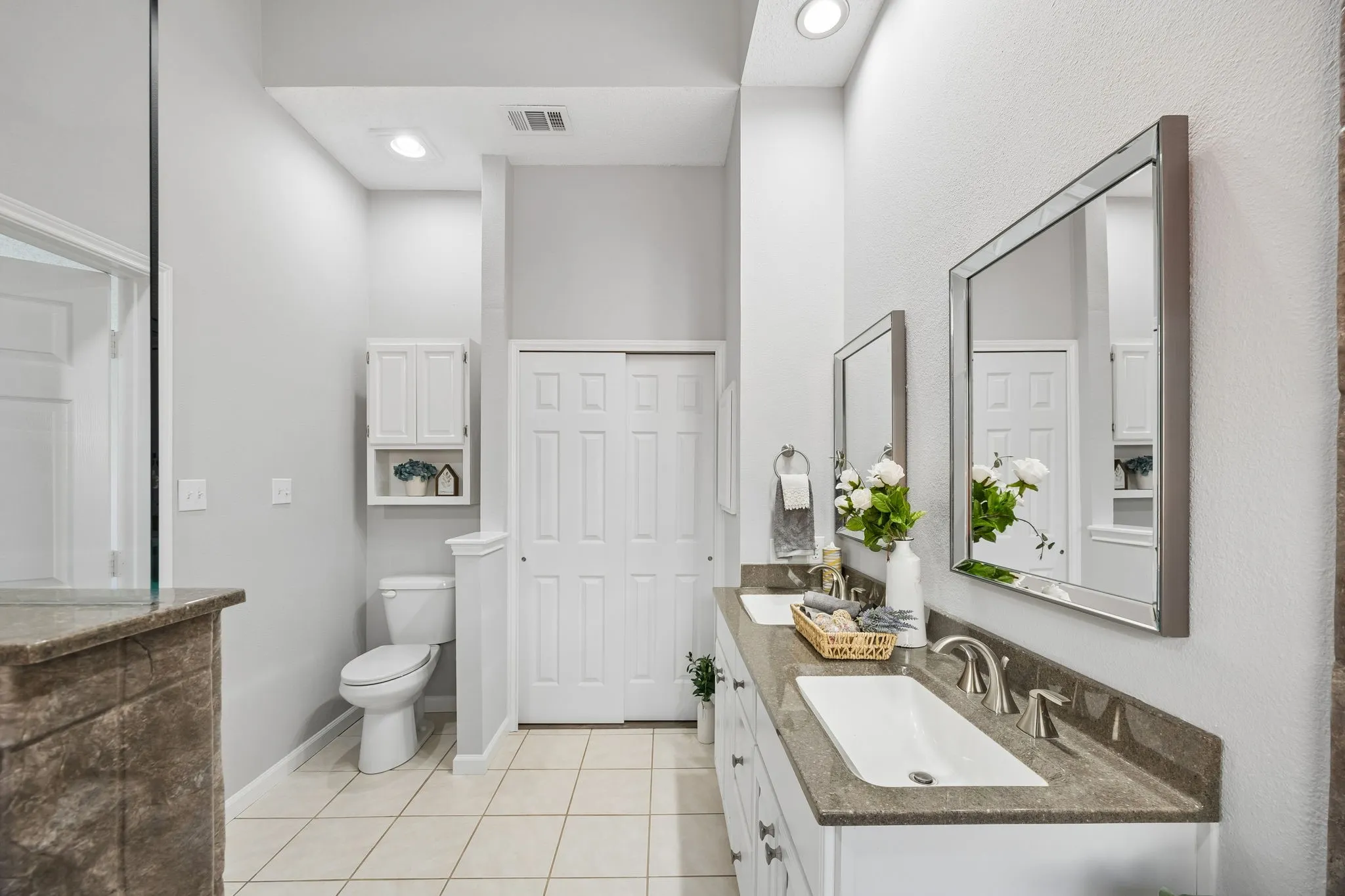 The beautifully updated primary bath (2019) features quartz countertops, dual sinks, updated lighting, elegant fixtures, a spacious walk-in shower, and a professionally organized walk-in closet