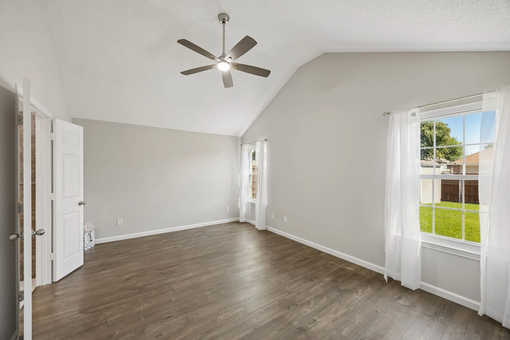 The primary suite offers a vaulted ceiling, new brushed-nickel ceiling fan, and peaceful backyard views.