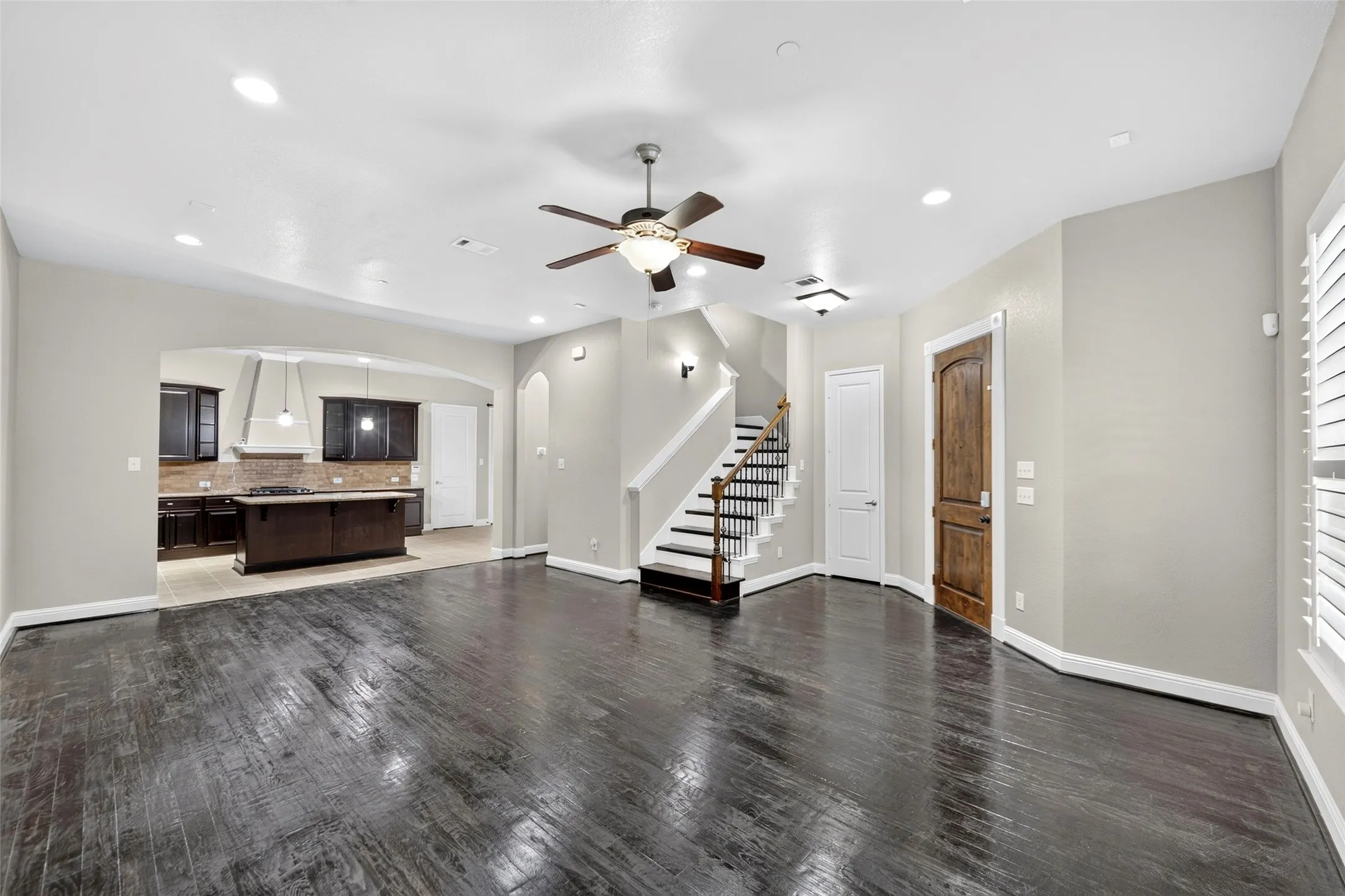 Dark wood-finish flooring throughout, recessed lighting, and a ceiling fan