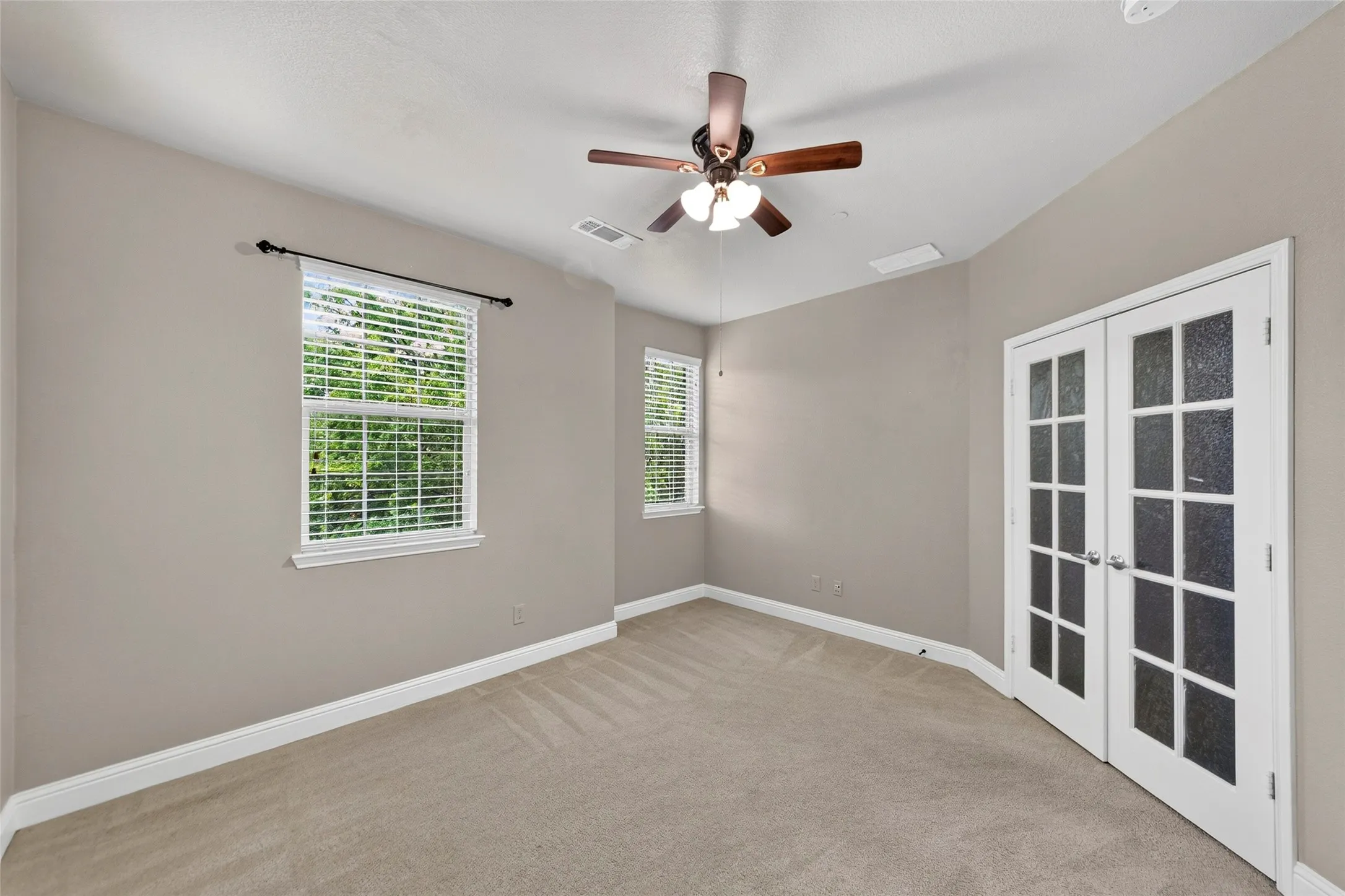 Carpeted flooring, white trim, dual pane windows, French doors with frosted glass, and a ceiling fan with integrated lighting