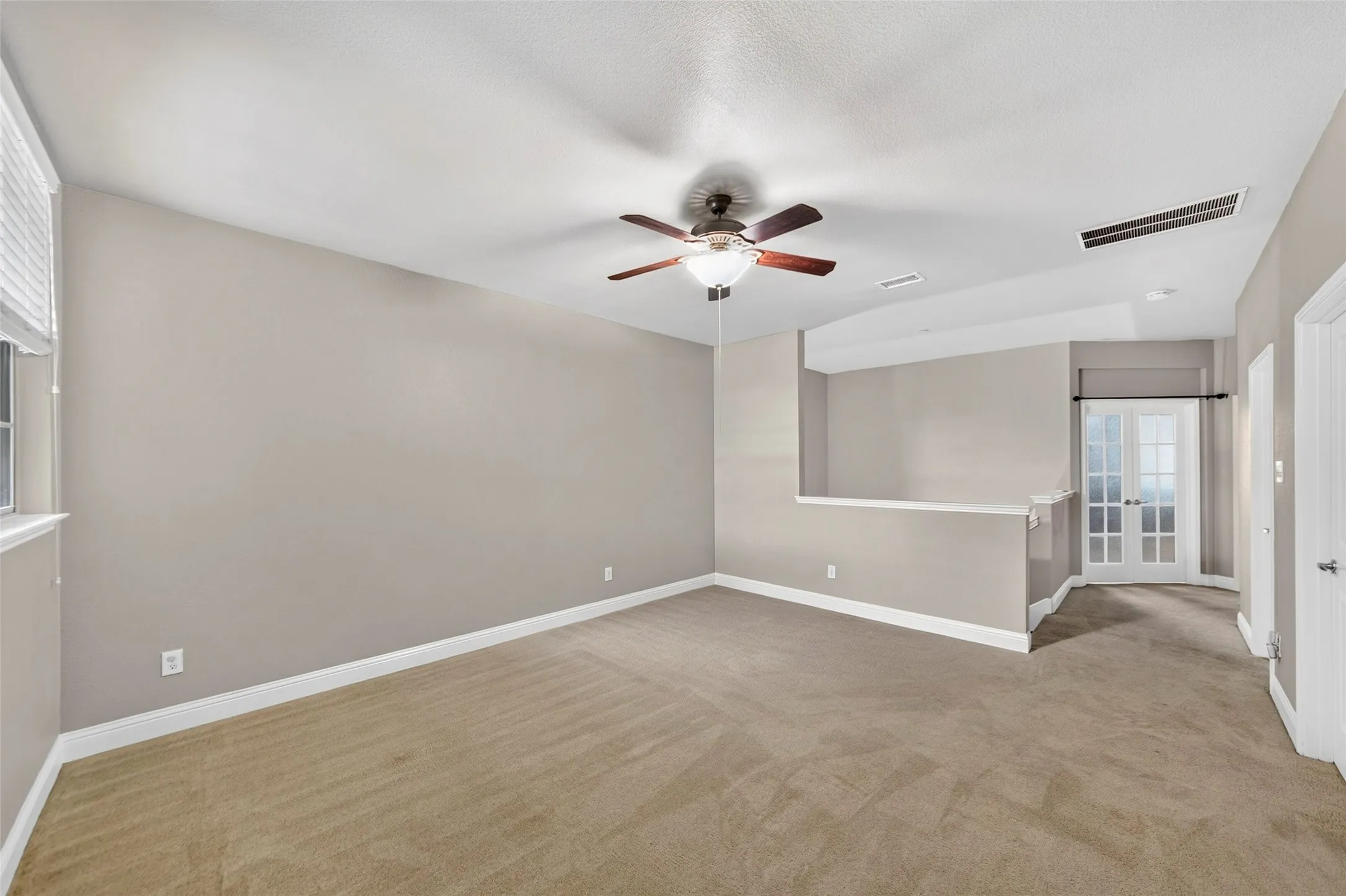 Spacious room featuring carpet flooring, a ceiling fan with integrated lighting, and a window with blinds