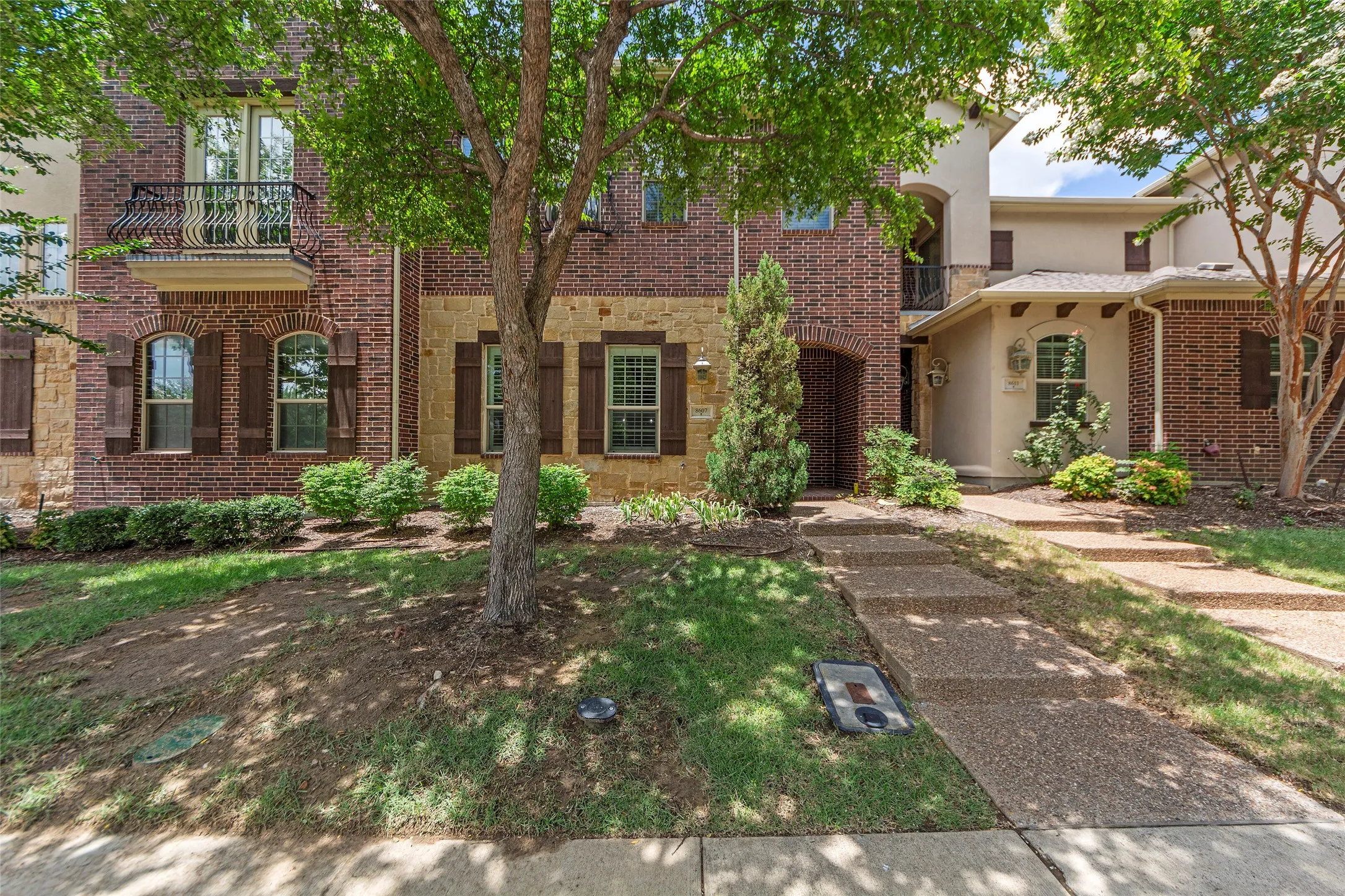 Brick and stone exterior with arched windows, decorative shutters, and a wrought iron balcony
