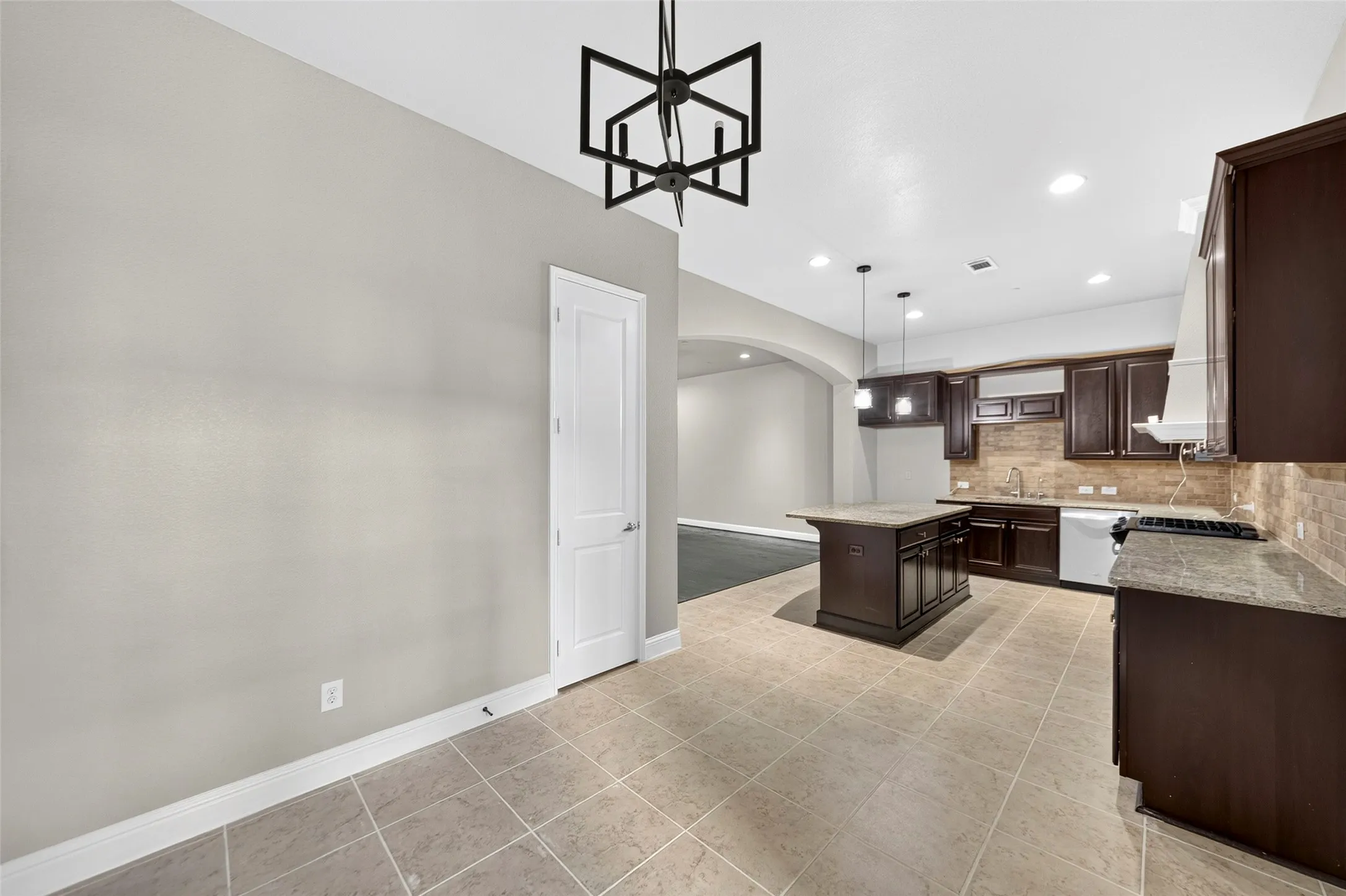 Kitchen featuring a central island, dark wood cabinetry, light-toned tile flooring, and recessed lighting