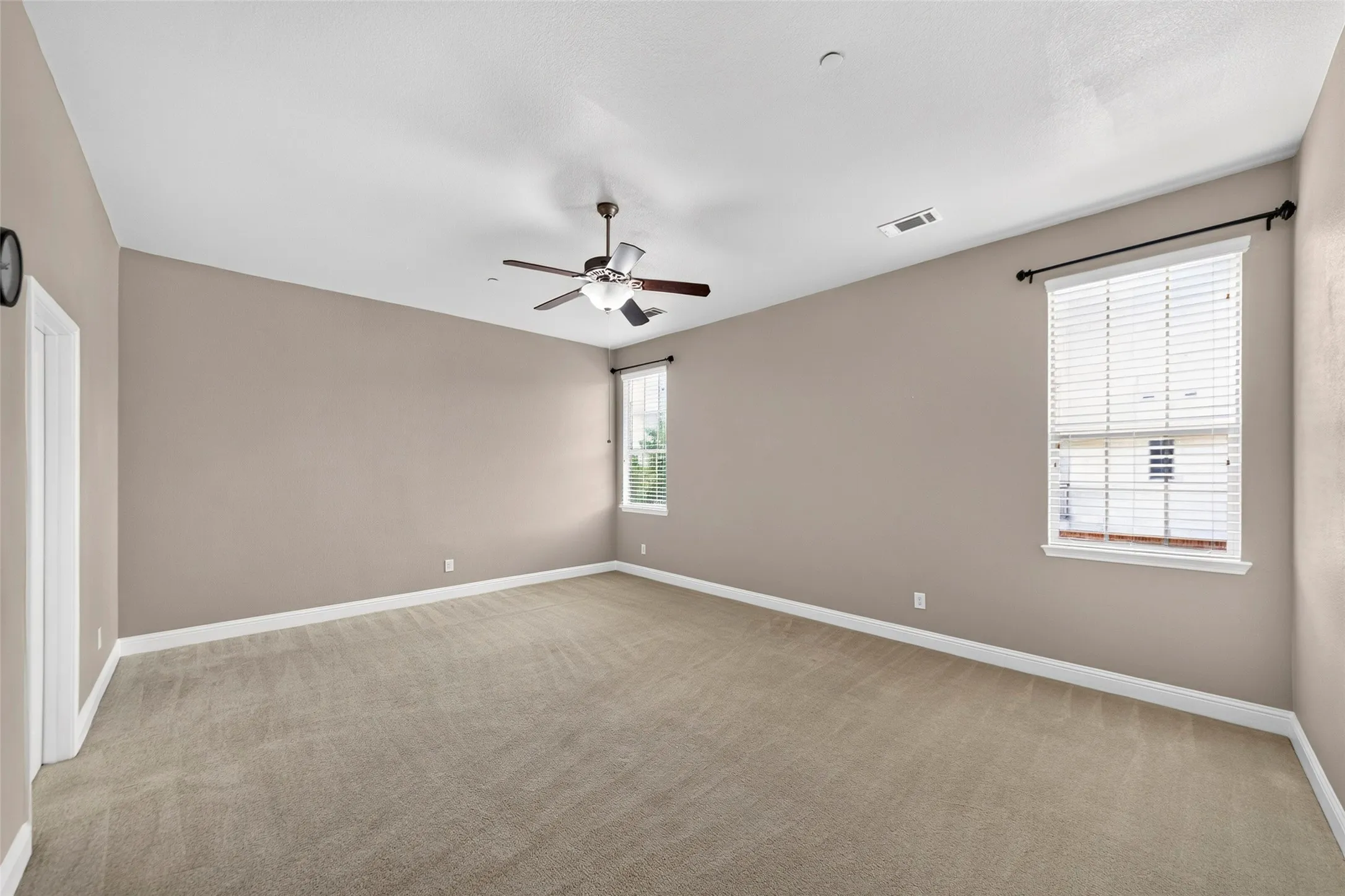 Neutral tone walls with white trim, carpeting, and a ceiling fan