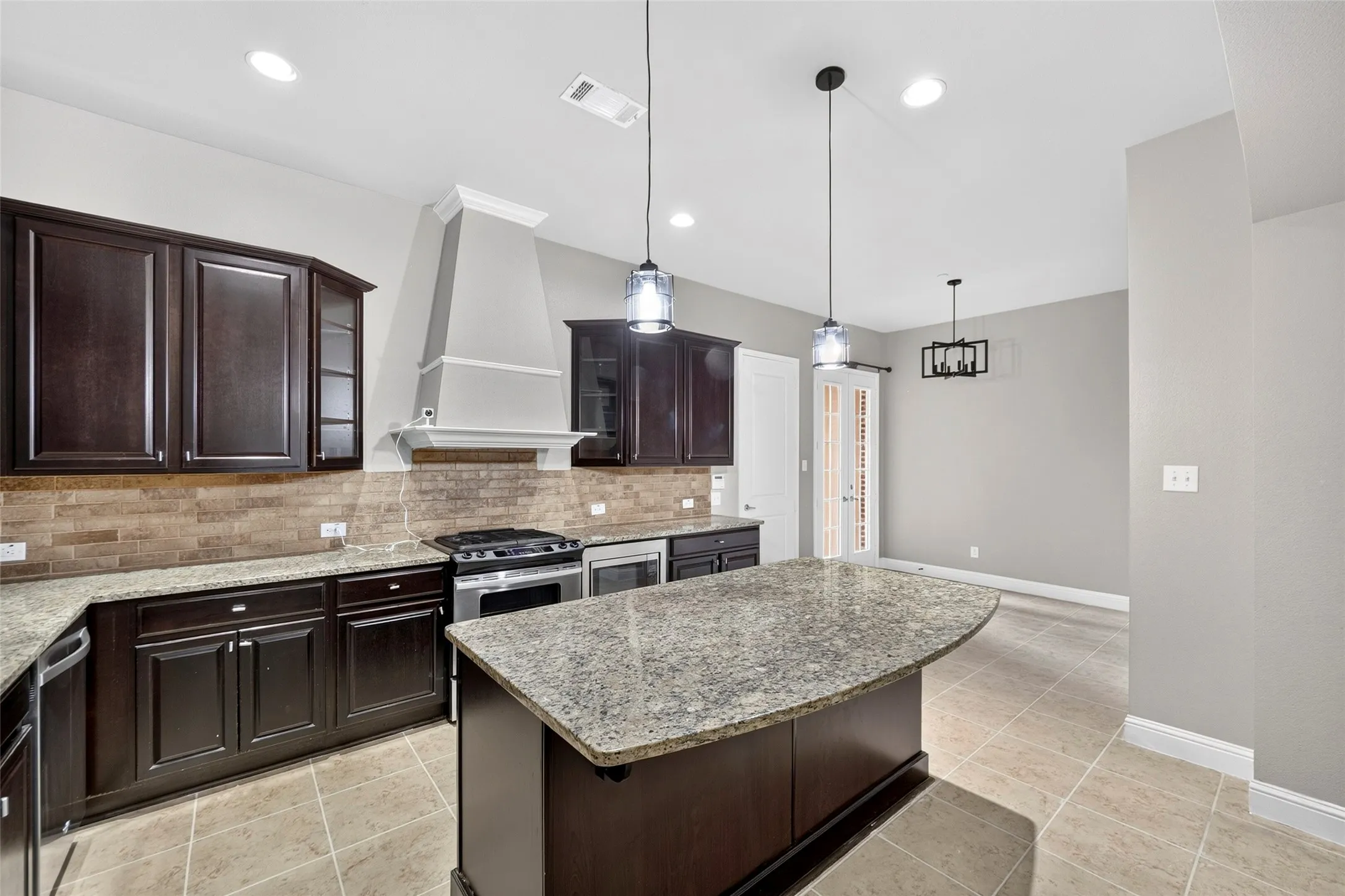 Kitchen featuring dark wood cabinetry, light-toned countertop surfaces, stainless steel appliances, a tile backsplash, and recessed lighting