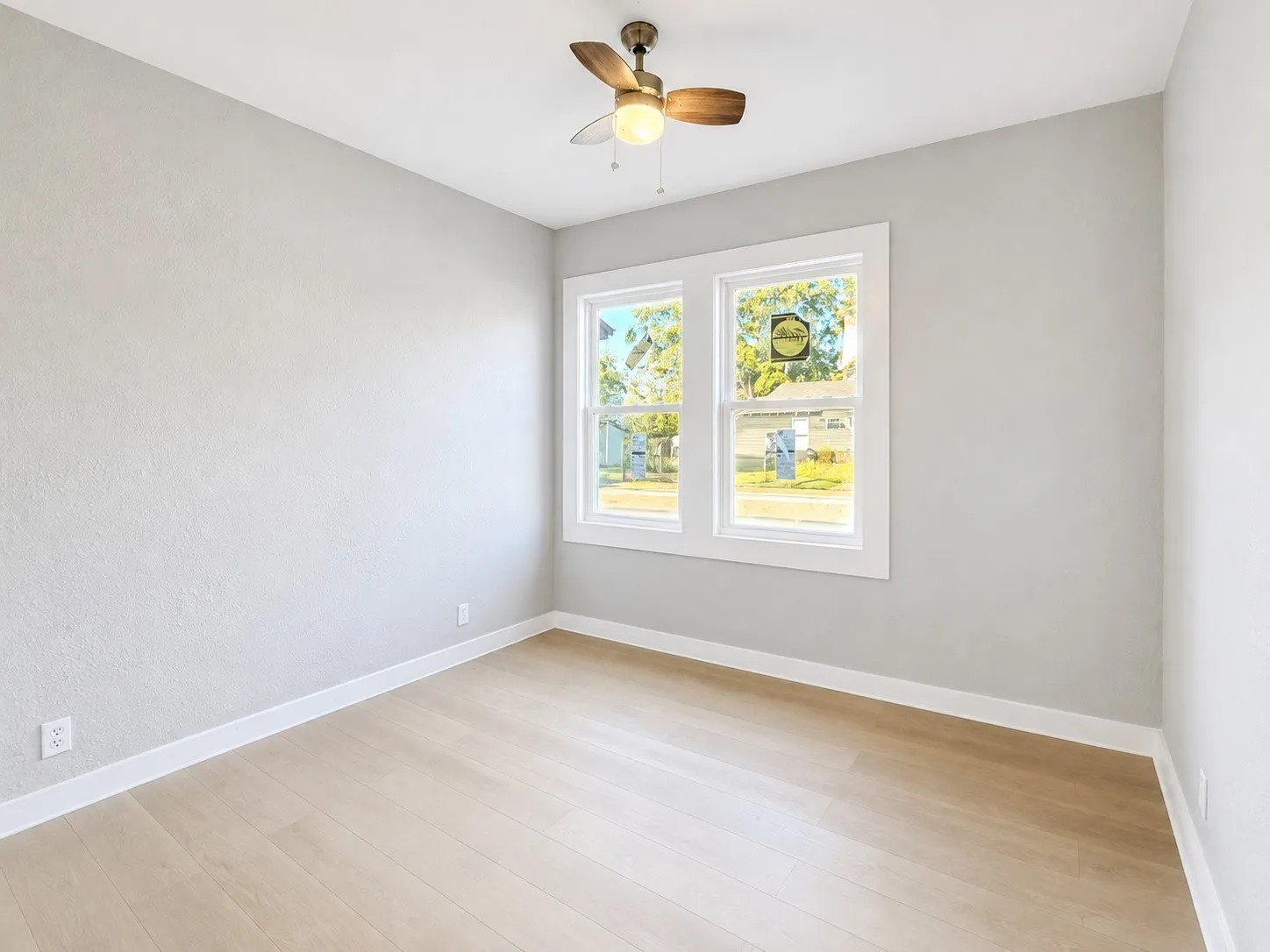 Light-toned wood-finish flooring, white trim, and a ceiling fan with integrated lighting