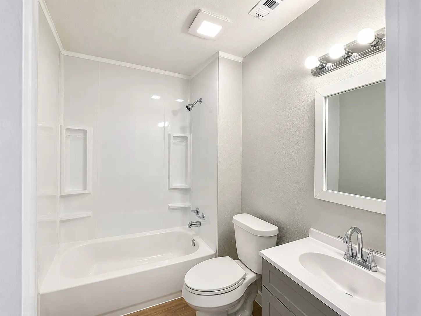 White tub and shower combination with integrated shelving