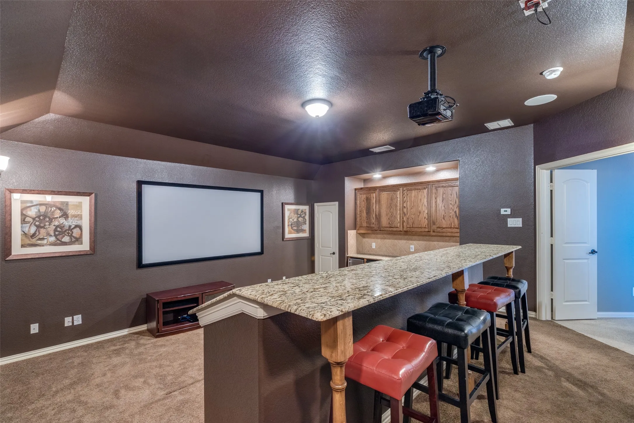 Media room featuring a built-in wet bar with wood cabinetry, light-toned countertop, and recessed lighting
