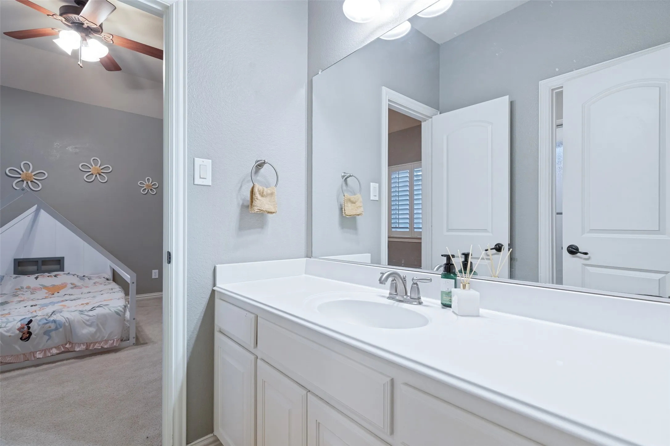 Vanity with an integrated sink, white cabinetry, a large wall-mounted mirror, and a chrome faucet