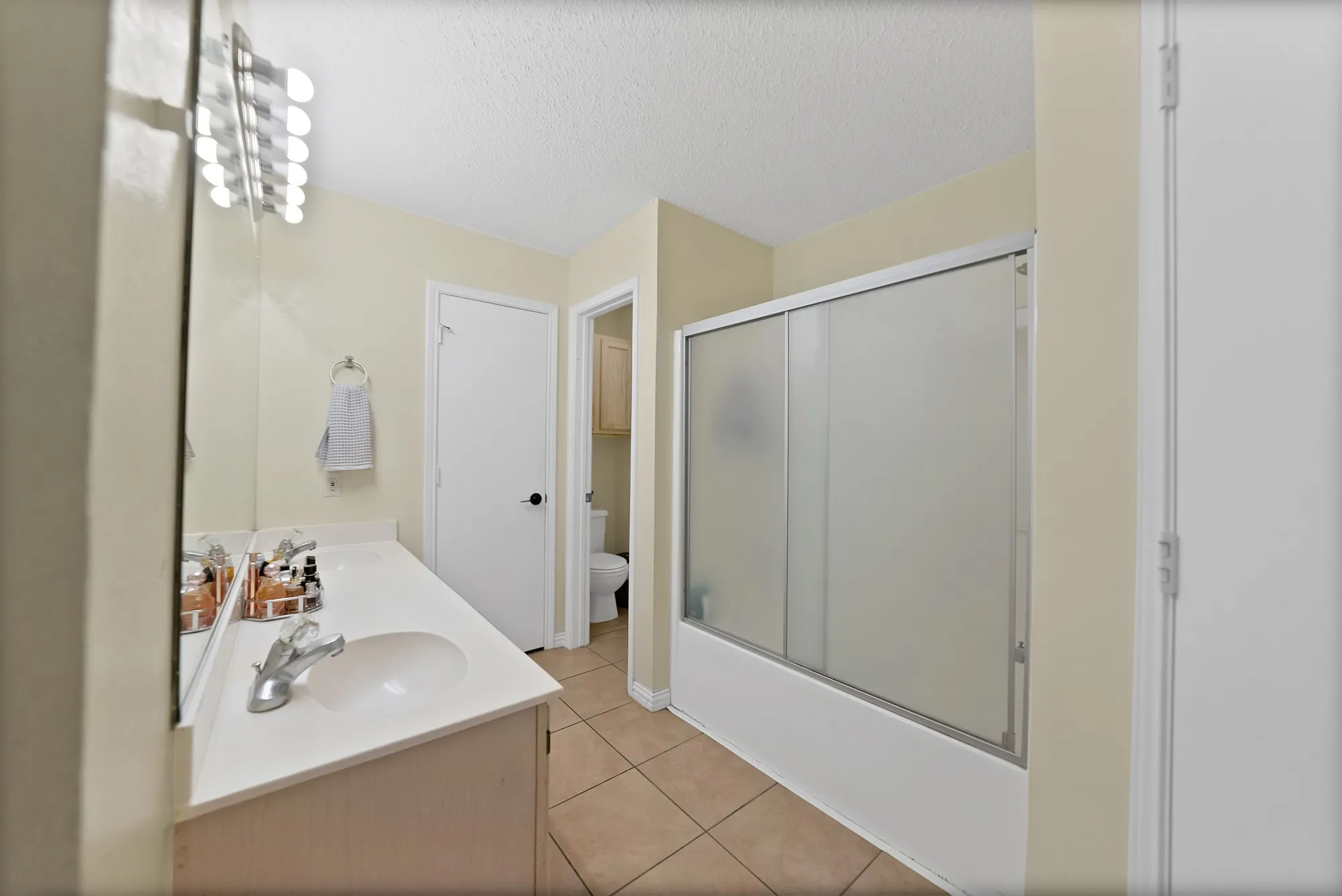 White vanity with integrated sink, chrome faucet, and mirrored medicine cabinet