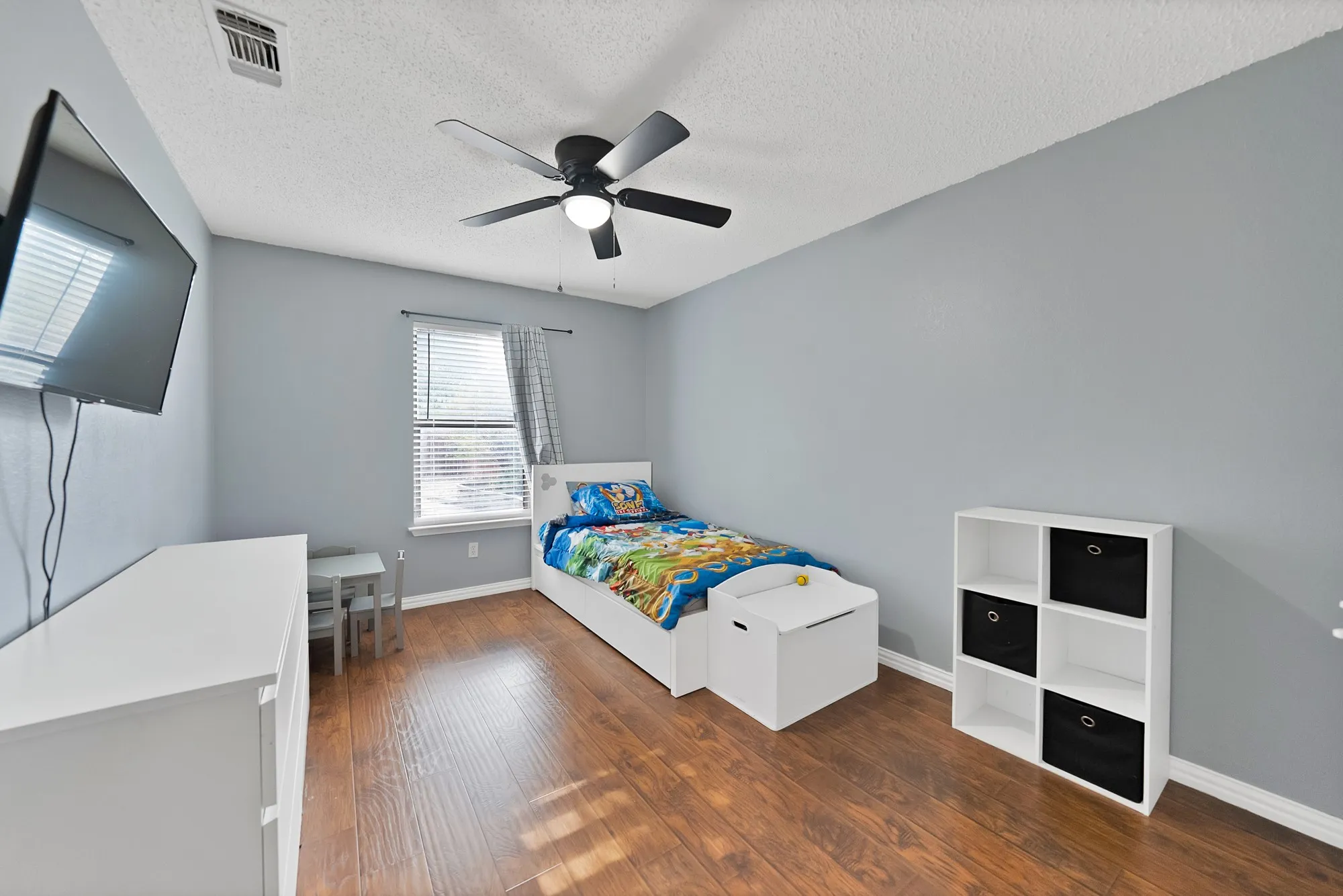 Wood-finish flooring, ceiling fan, and window with blinds