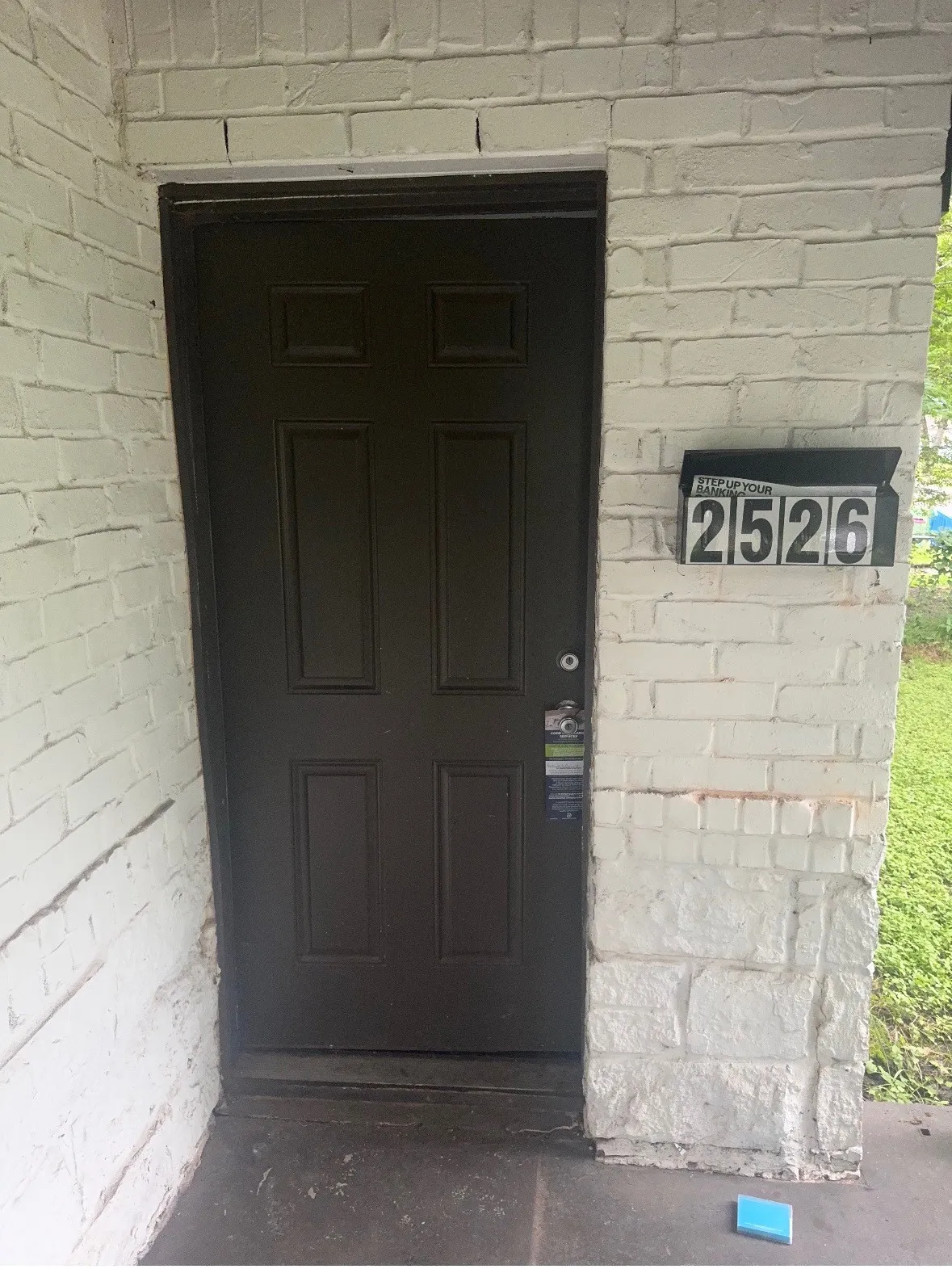 Painted brick exterior featuring a panel-style entry door and wall-mounted house numbers