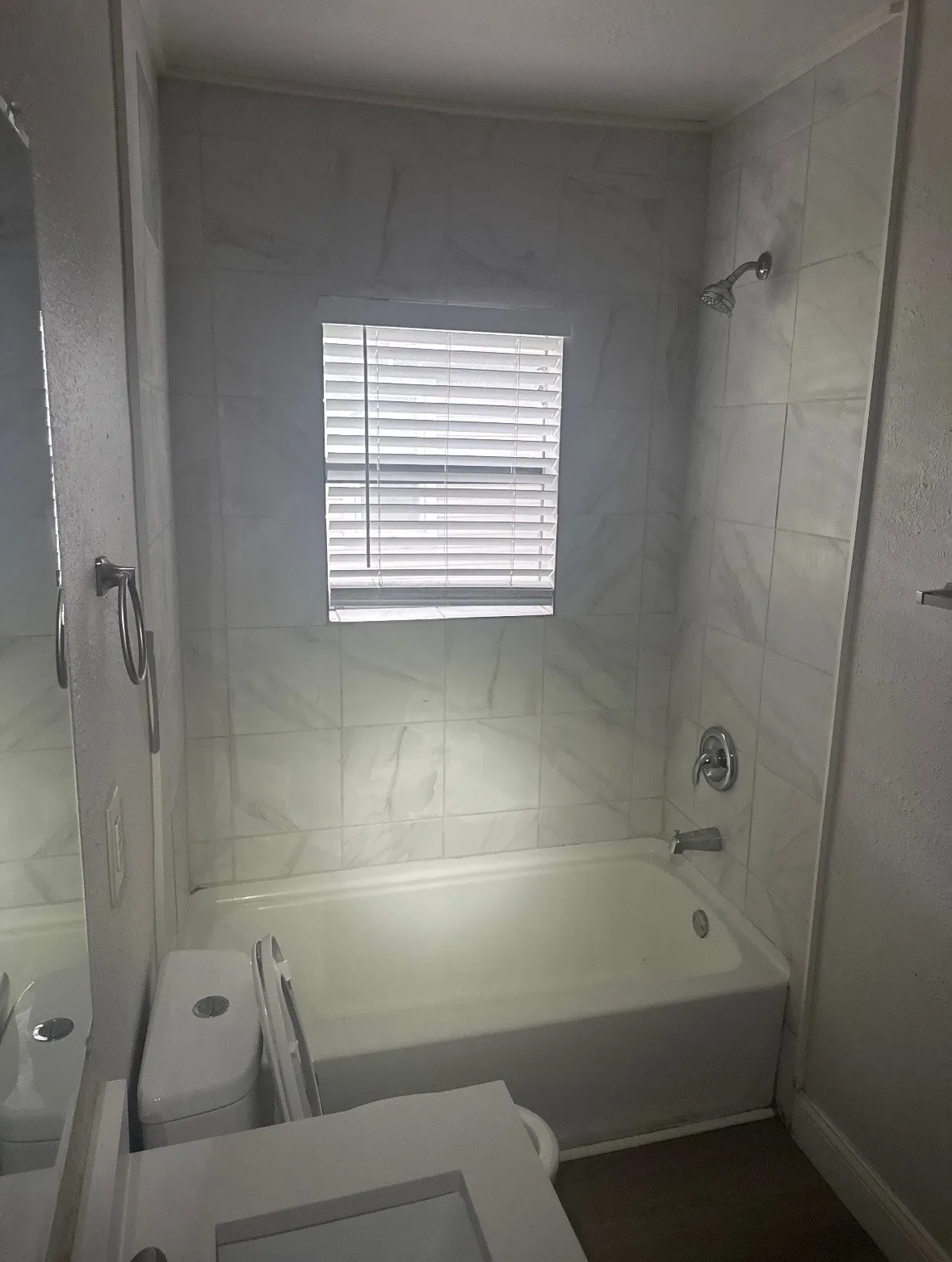 Bathtub with chrome fixtures, white subway tile surround, and an integrated window