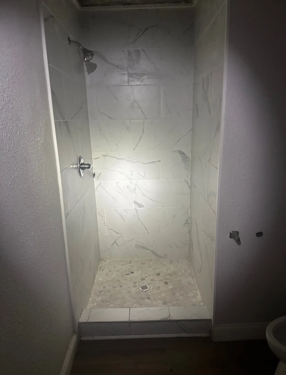 Shower stall with large format wall tiles and a mosaic-tiled floor
