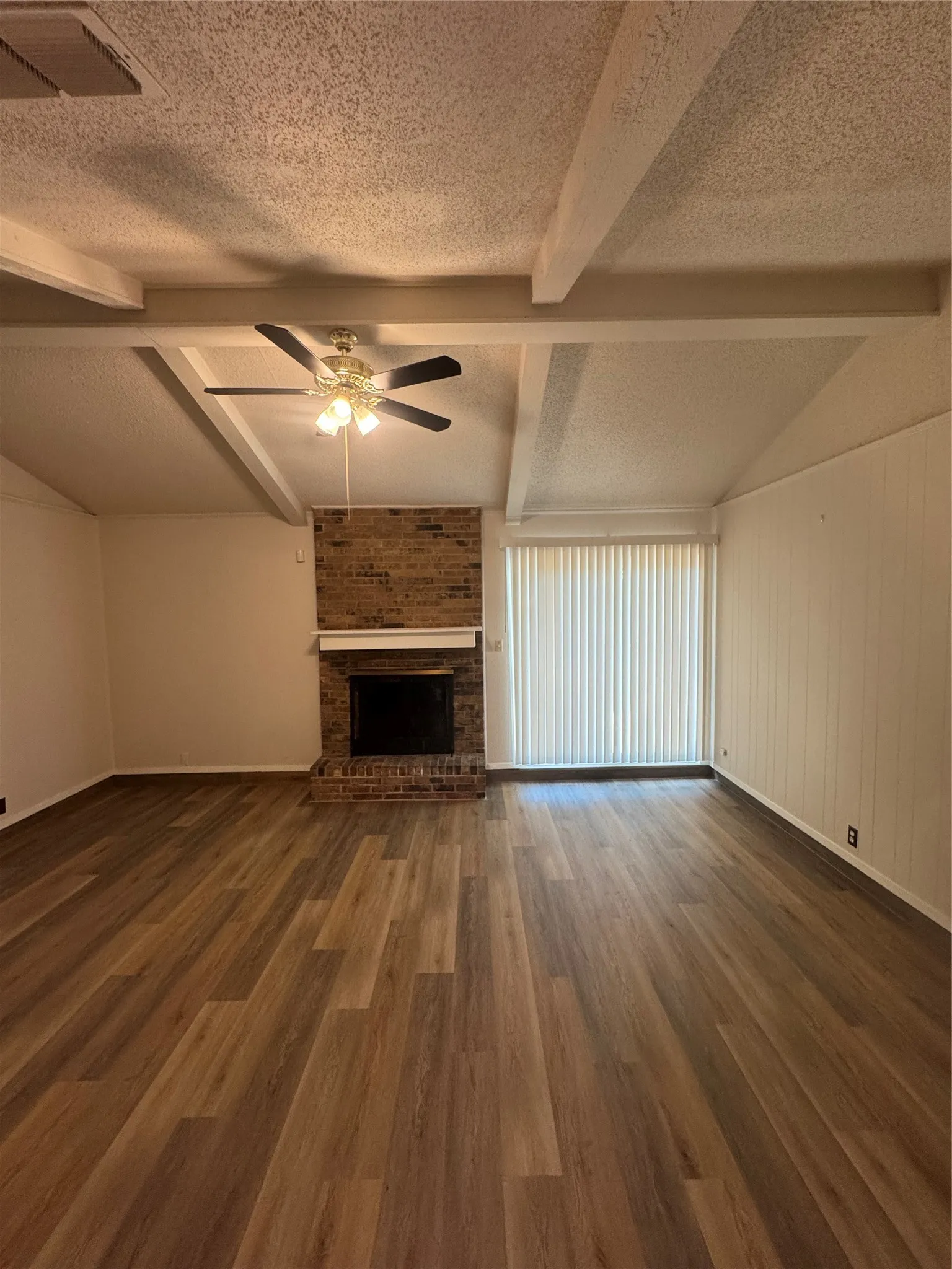 Expansive living area Featuring Luxury Vinyl Plank flooring, a brick-surround fireplace, Sliding Patio Door to Patio, and a ceiling fan