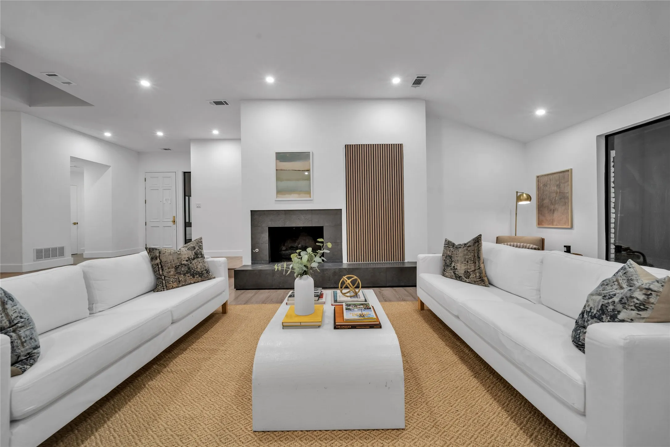 Living area with recessed lighting, visible vents, and a fireplace with raised hearth