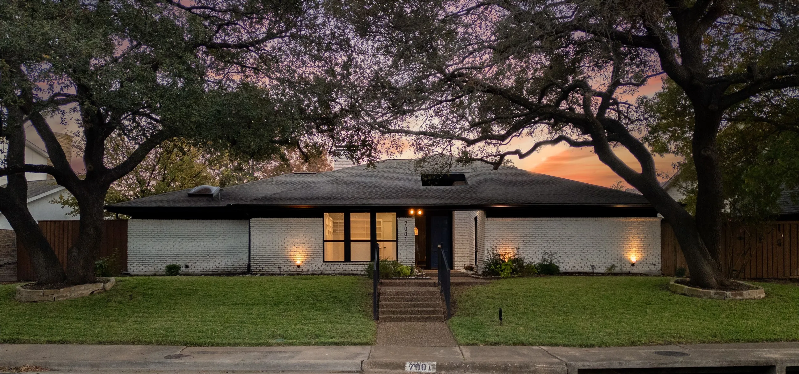 Mid-century modern home featuring brick siding, a lawn, and fence