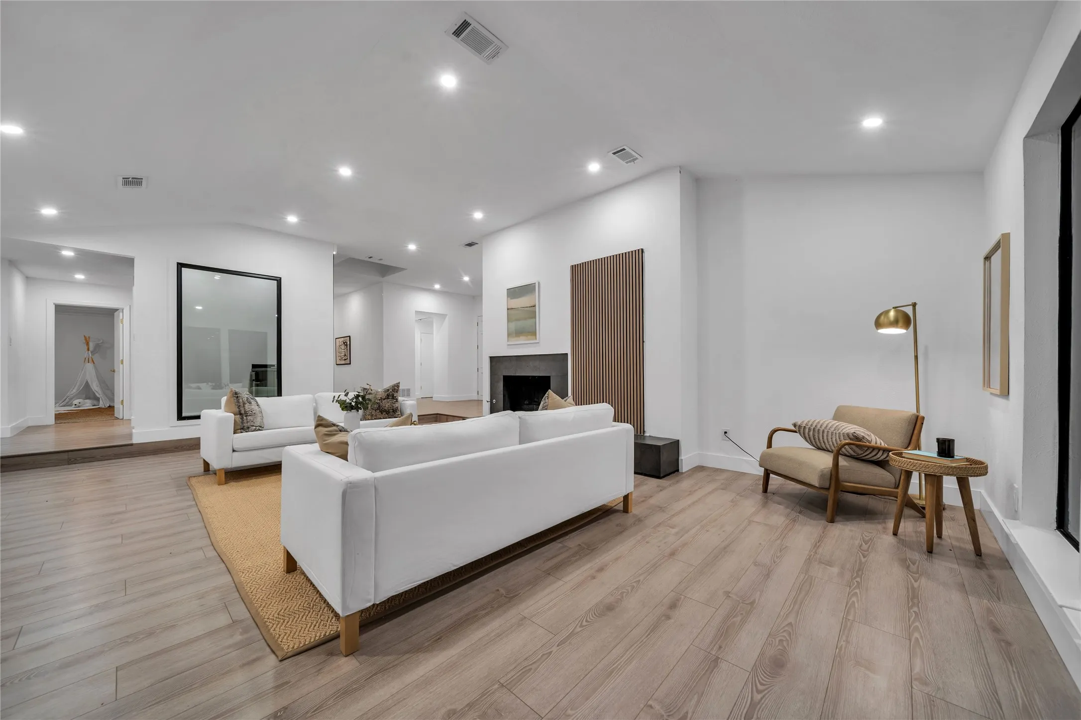 Living room featuring lofted ceiling, recessed lighting, visible vents, and light wood-type flooring