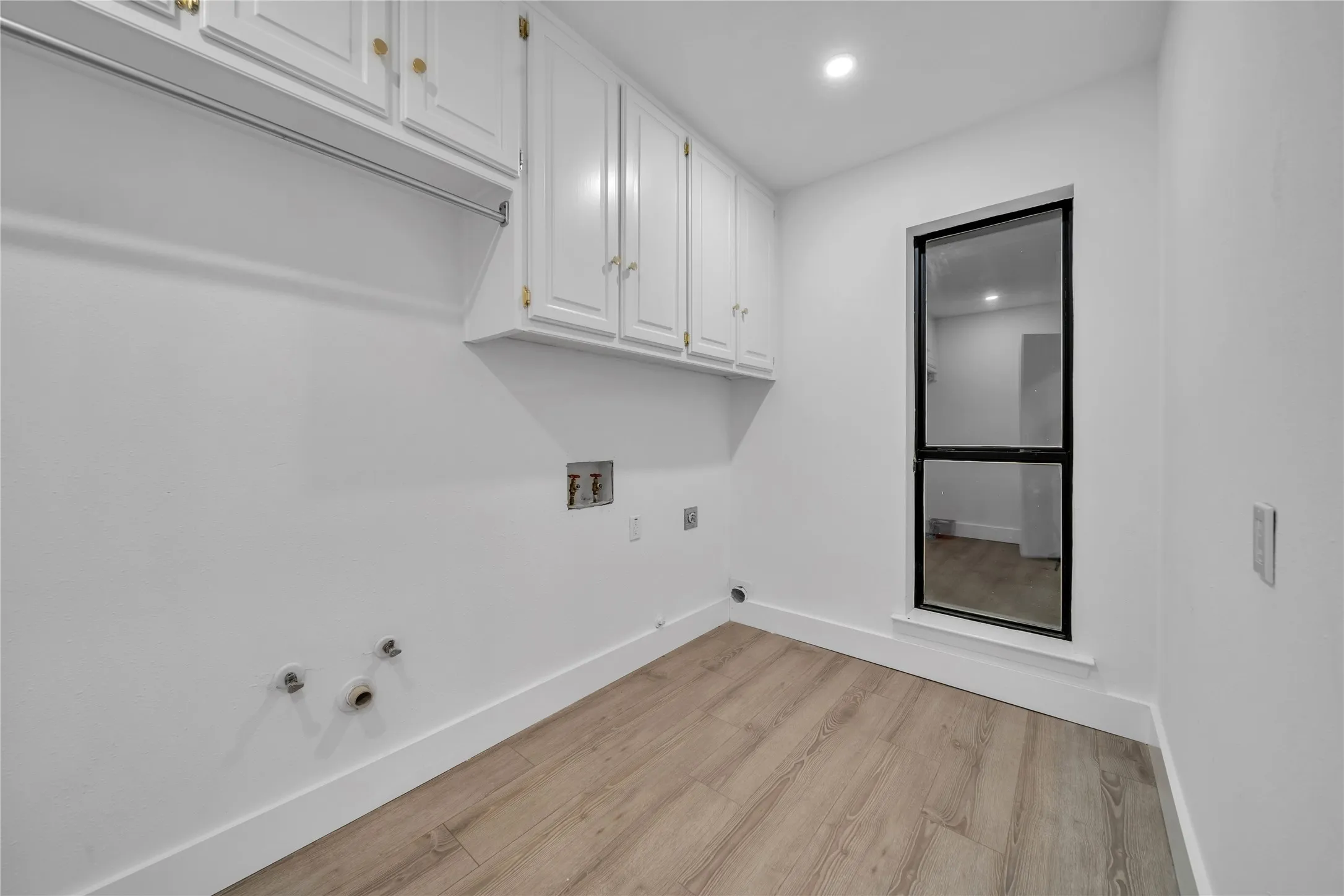 Washroom with hookup for a gas dryer, cabinet space, light wood finished floors, baseboards, and hookup for a washing machine