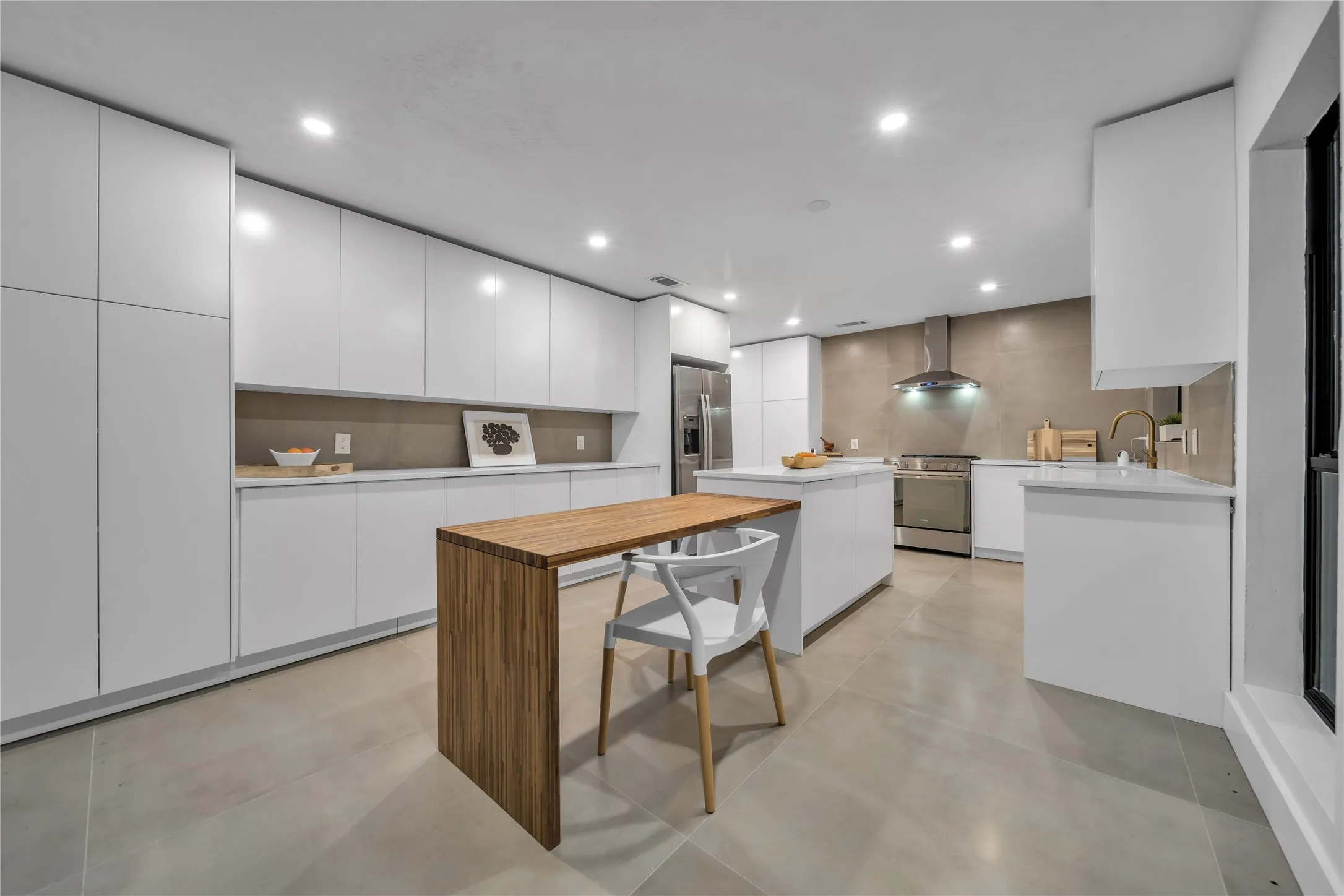 Kitchen with modern cabinets, backsplash, a center island, appliances with stainless steel finishes, and wall chimney range hood