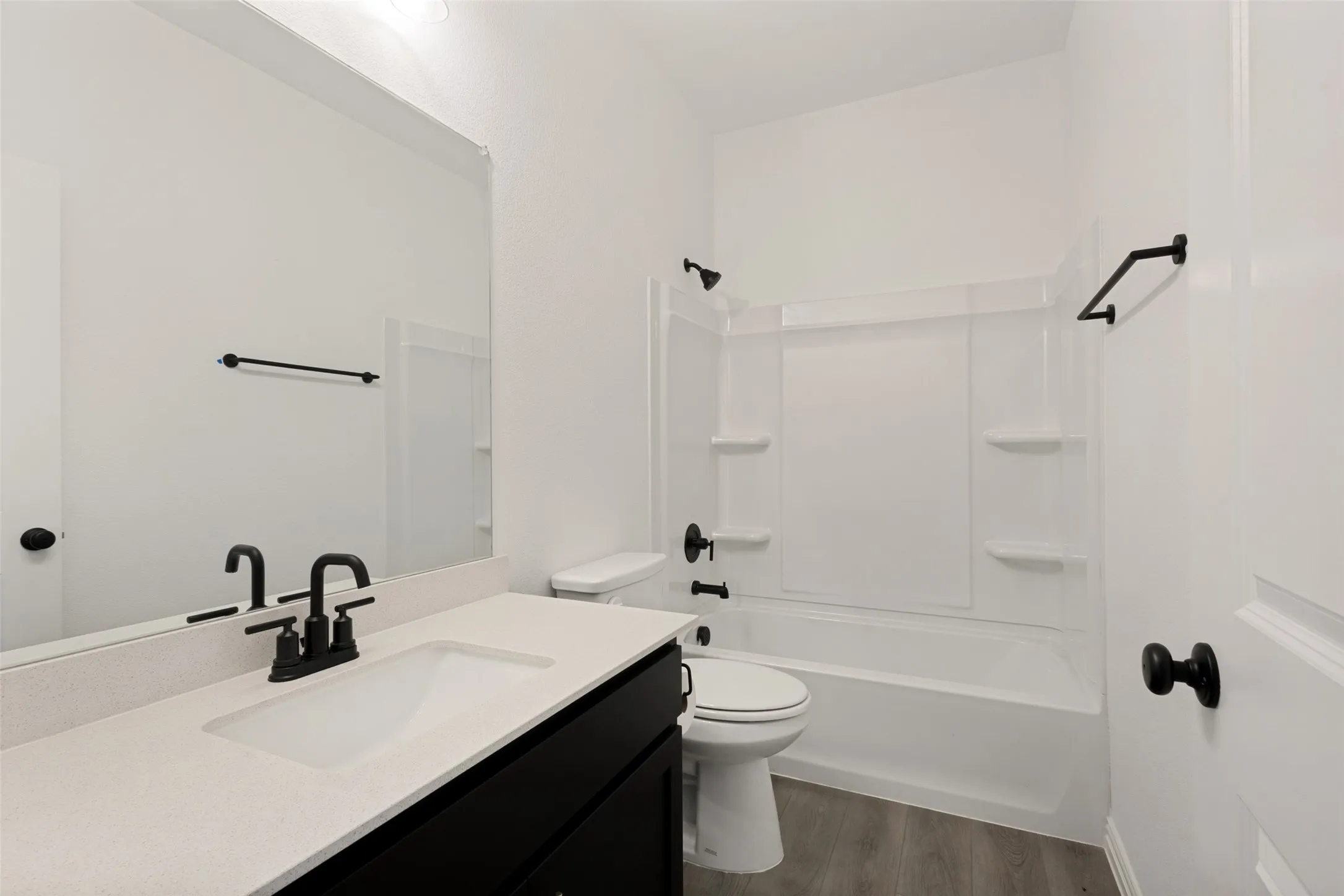 Bathroom featuring a single vanity with an undermount sink, a white countertop, dark cabinetry, and a shower-tub combination