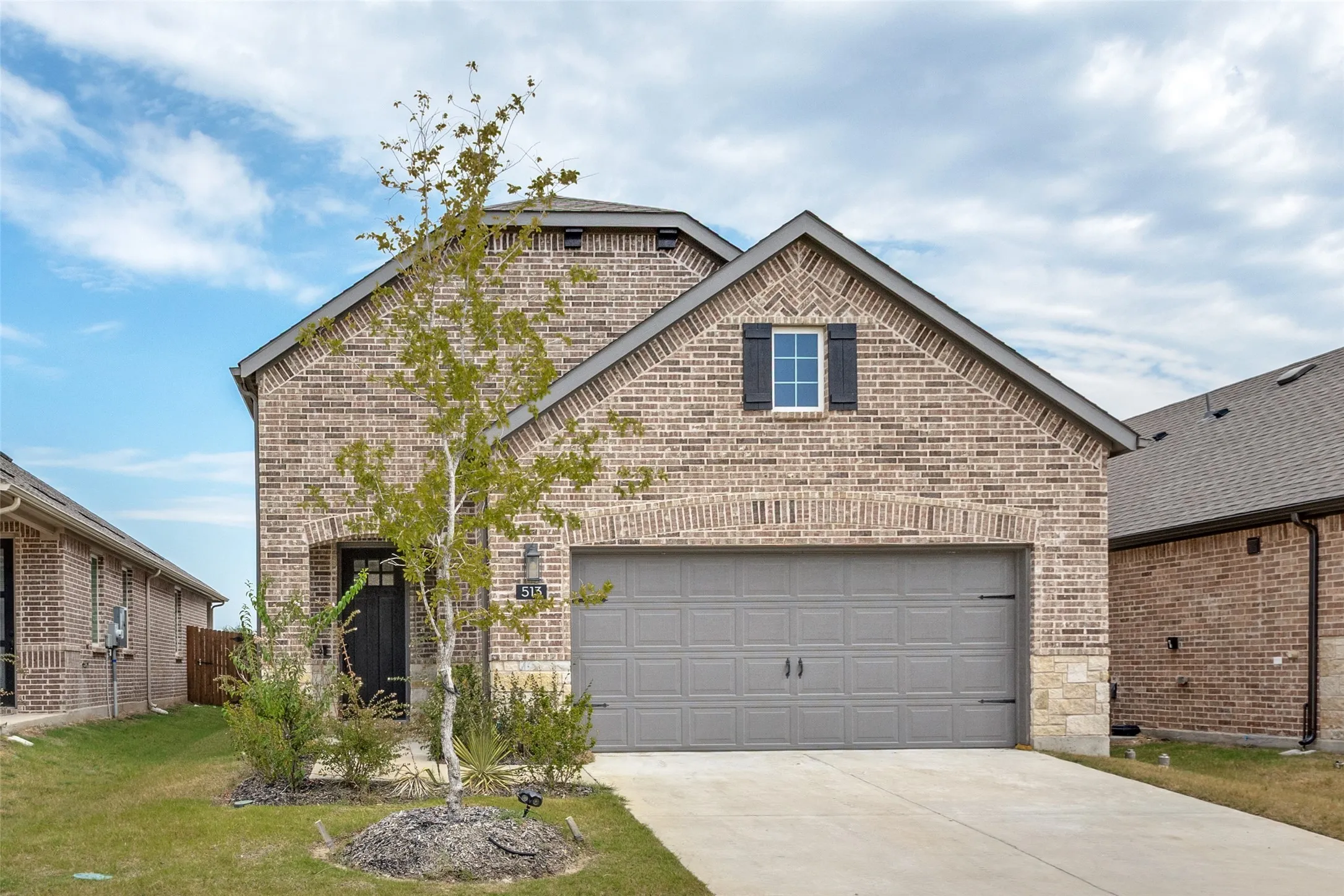 Brick exterior with stone accents, an attached two-car garage, and a covered entry