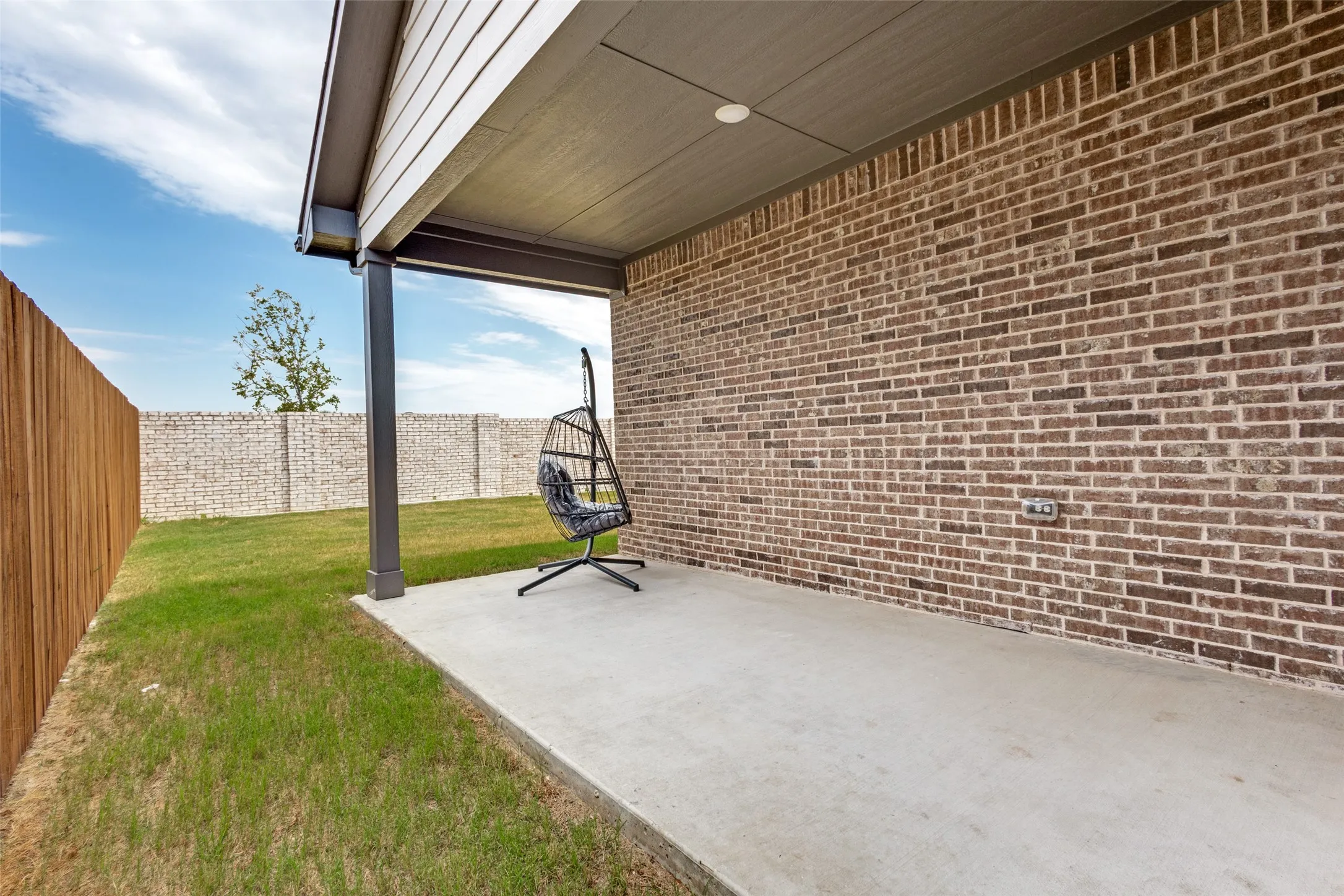 Covered patio featuring a concrete slab and brick exterior wall