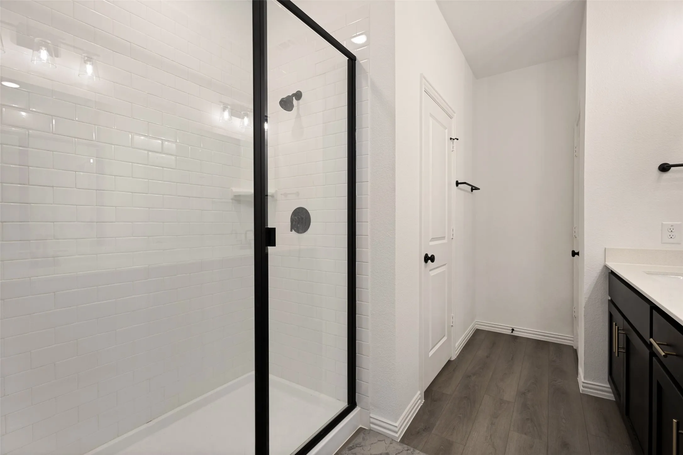 Shower with black-framed glass enclosure, white subway tile surround, and matte black fixtures