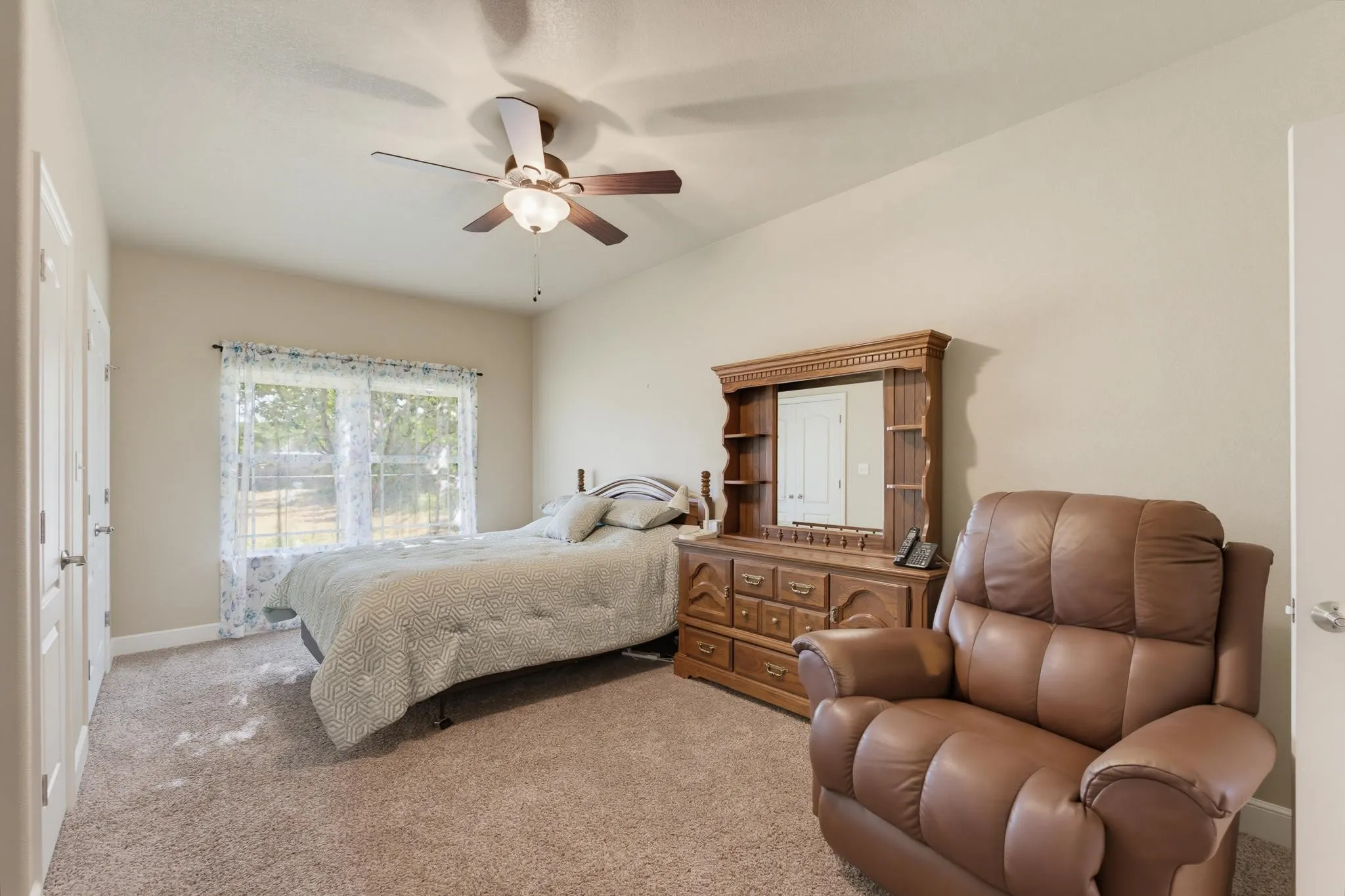 Neutral wall paint, ceiling fan, and carpeted flooring