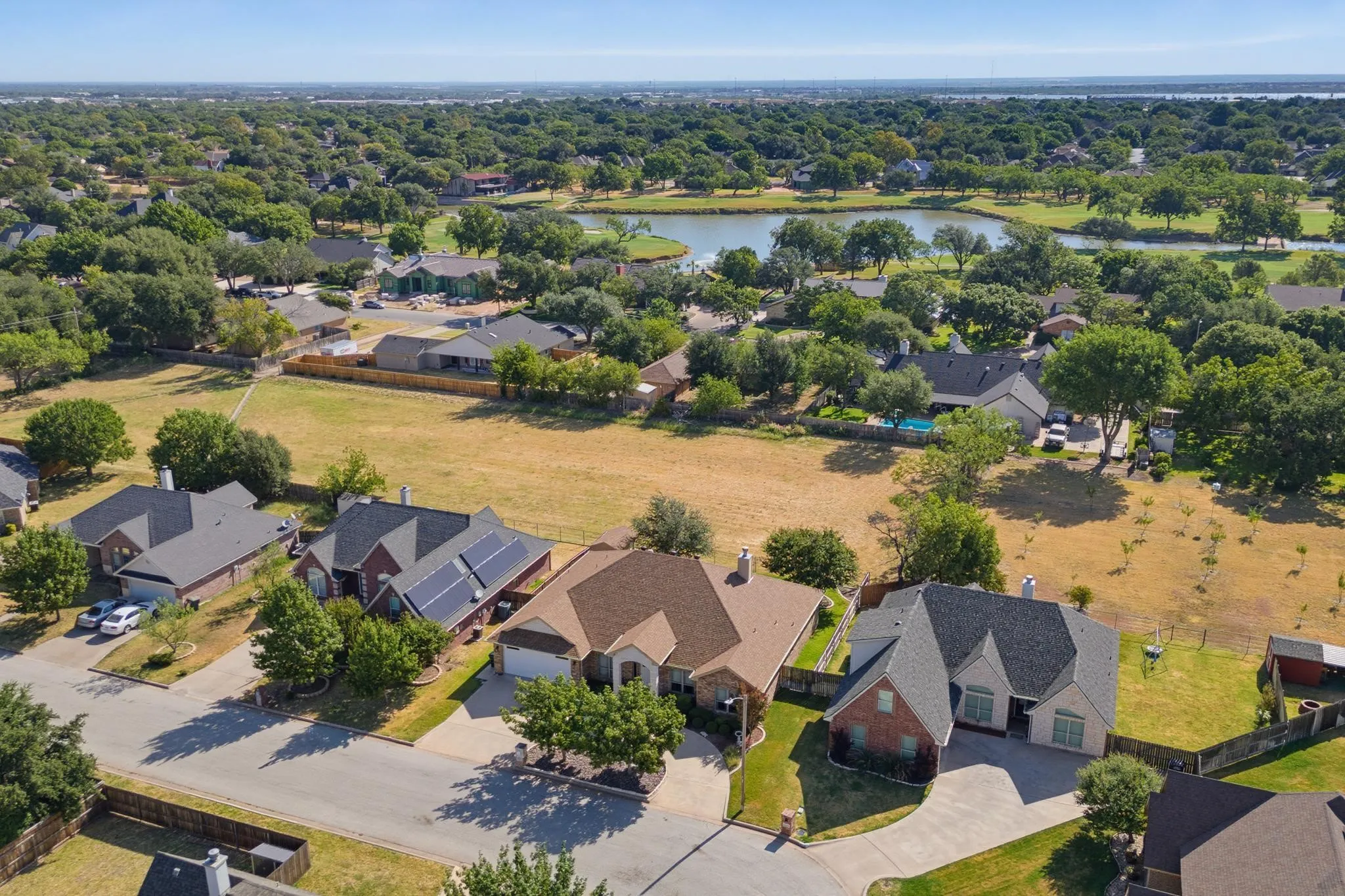 Expansive neighborhood featuring mature trees, residential properties, paved streets, and a prominent water feature