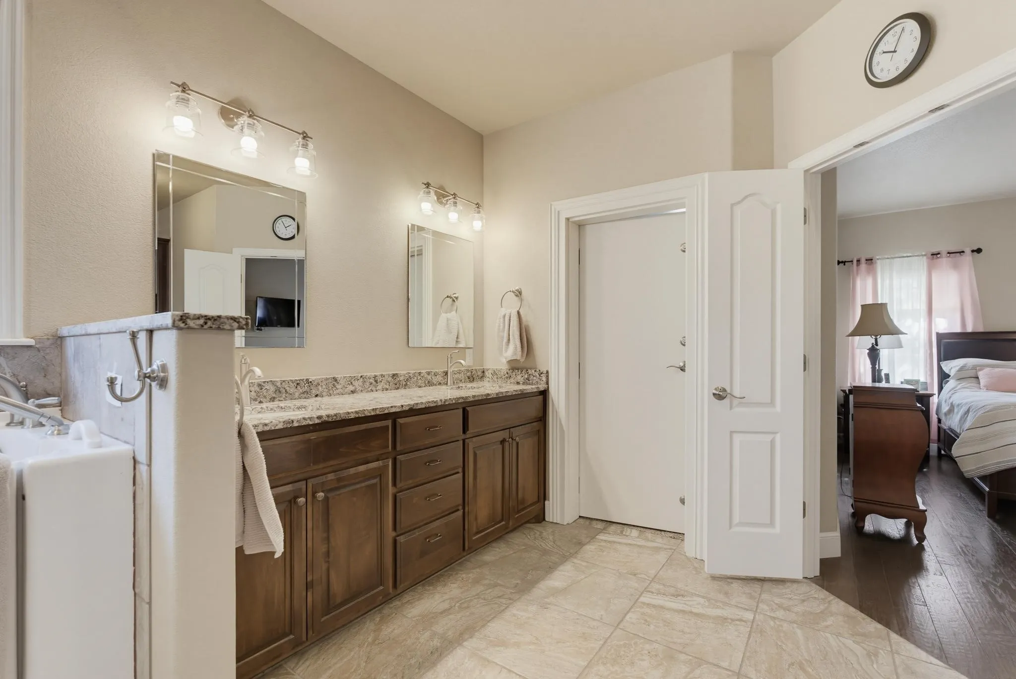 Dual vanity with granite countertops, wood-finish cabinetry, and tiled flooring