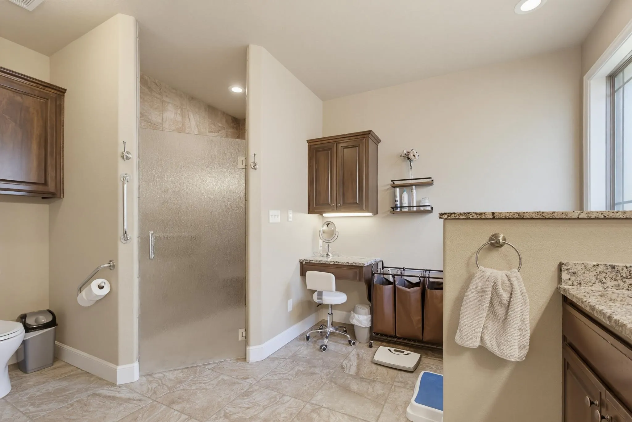 Tile flooring featuring a walk-in shower with textured glass enclosure, built-in cabinetry, and integrated vanity counter with under-cabinet lighting
