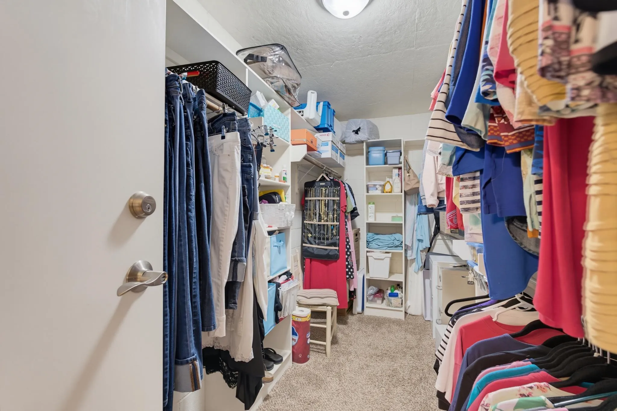 Walk-in closet with built-in shelving, multiple hanging rods, and carpet flooring