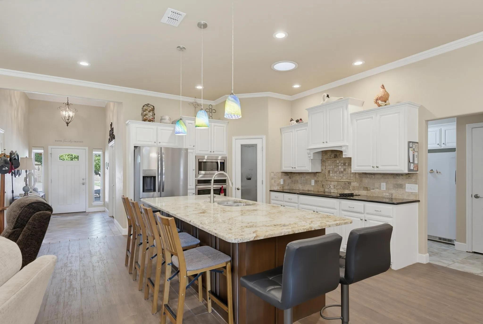 Kitchen featuring a large island with stone countertop, white cabinetry, stainless steel appliances, and wood-finish flooring