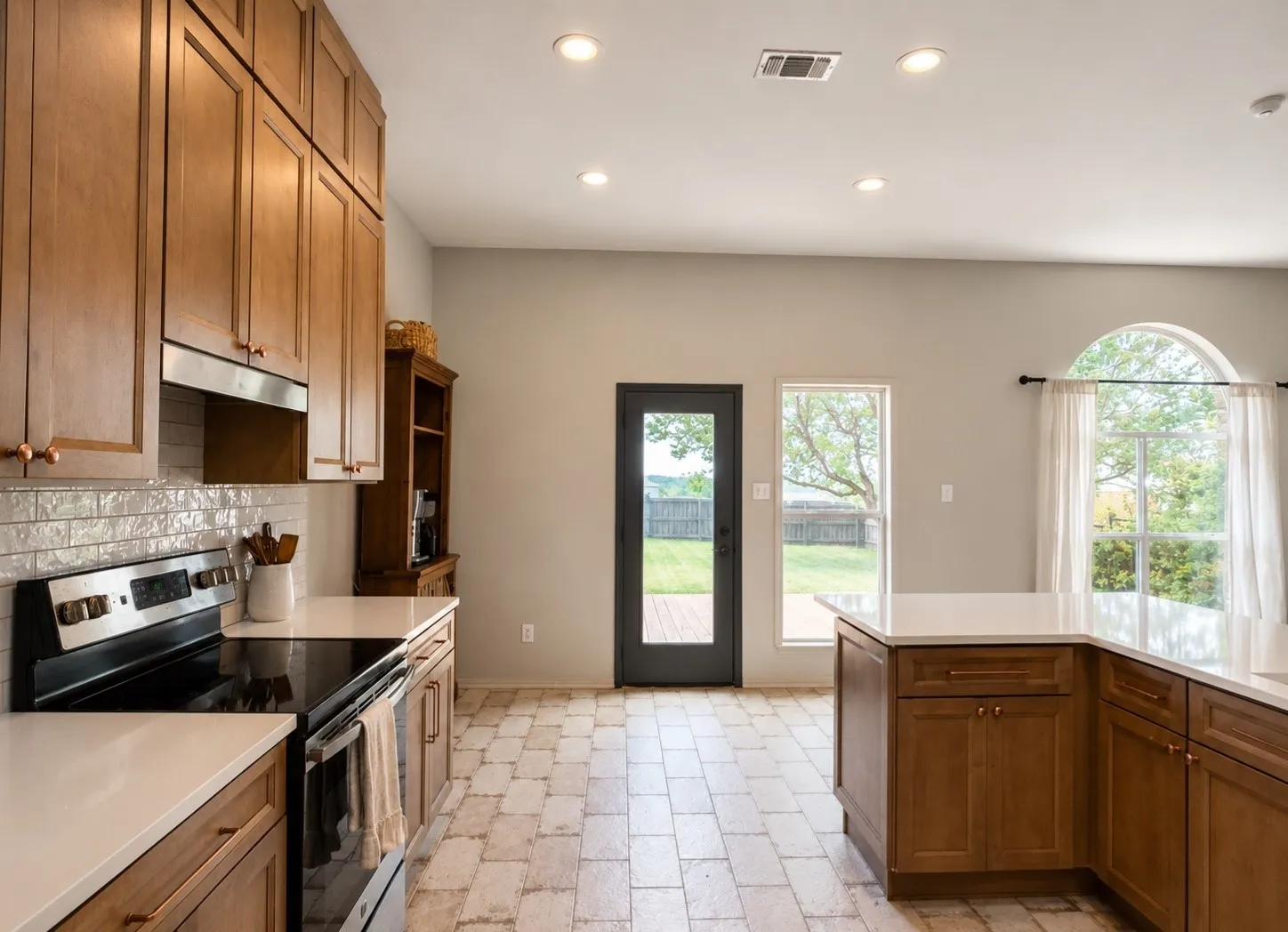 Kitchen featuring wood cabinetry, light-toned countertops, a subway tile backsplash, and stainless steel appliances