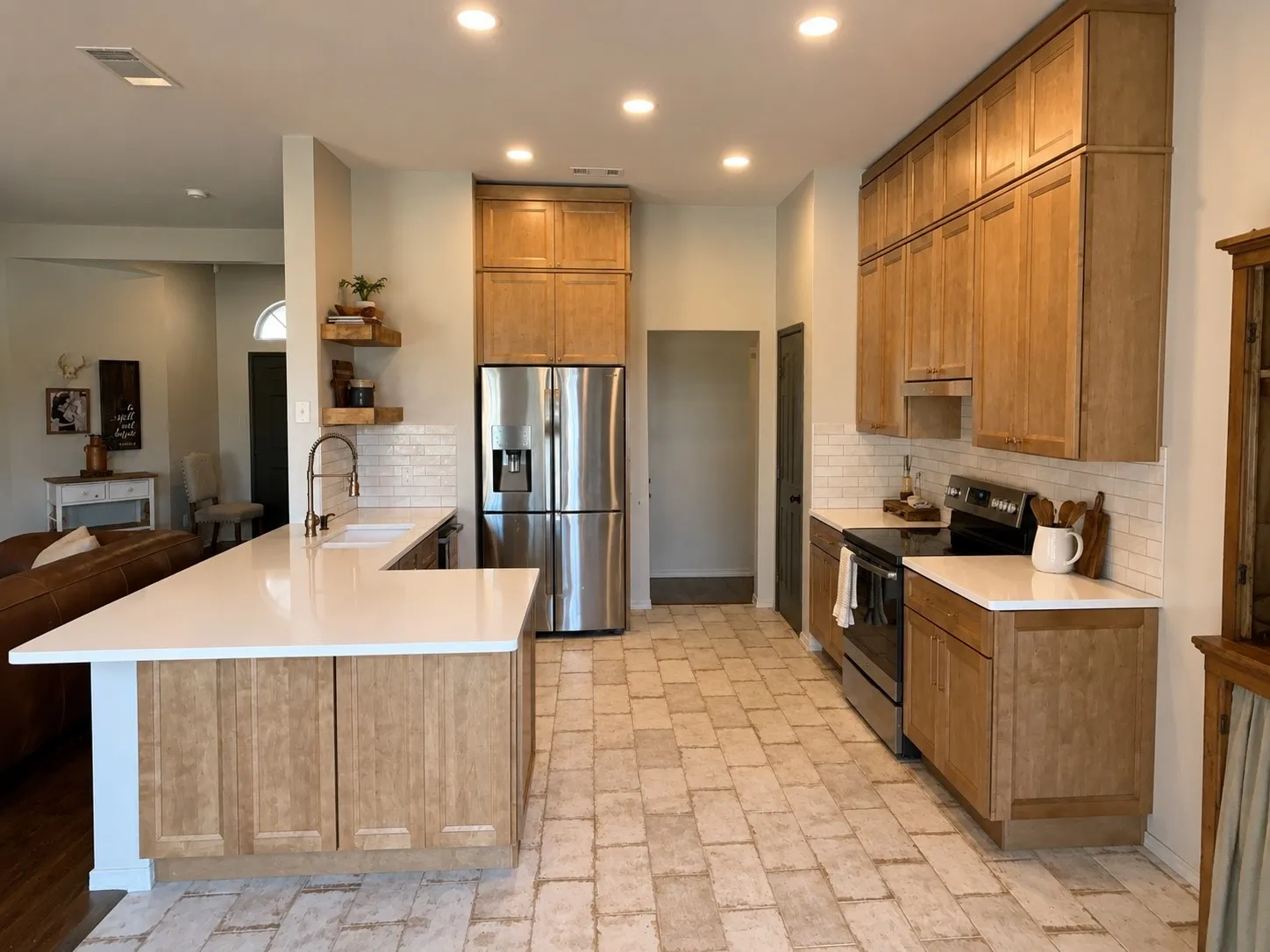 Open-concept kitchen featuring light wood-finish cabinetry, white subway tile backsplash, and light-toned, textured tile flooring