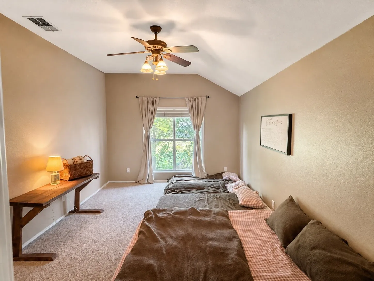 Carpeted room featuring a vaulted ceiling with a ceiling fan, a window with curtains, and a built-in wood shelf along one wall