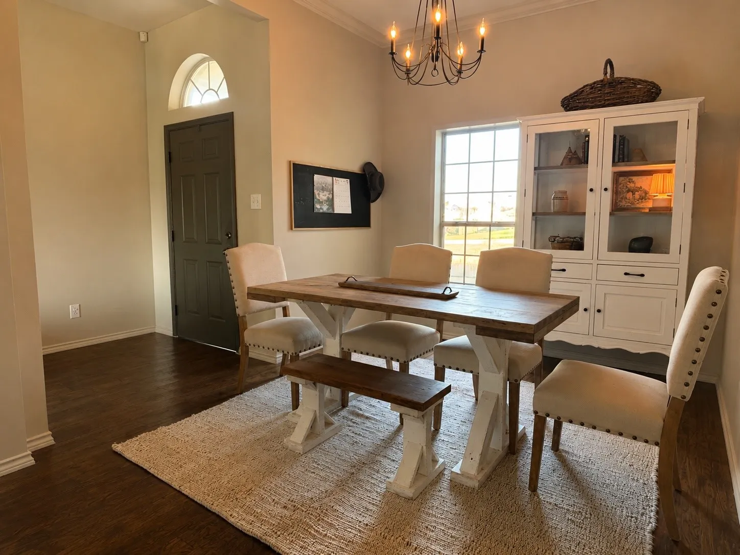 Spacious dining area featuring dark wood-finish flooring, a contemporary chandelier, and a prominent window