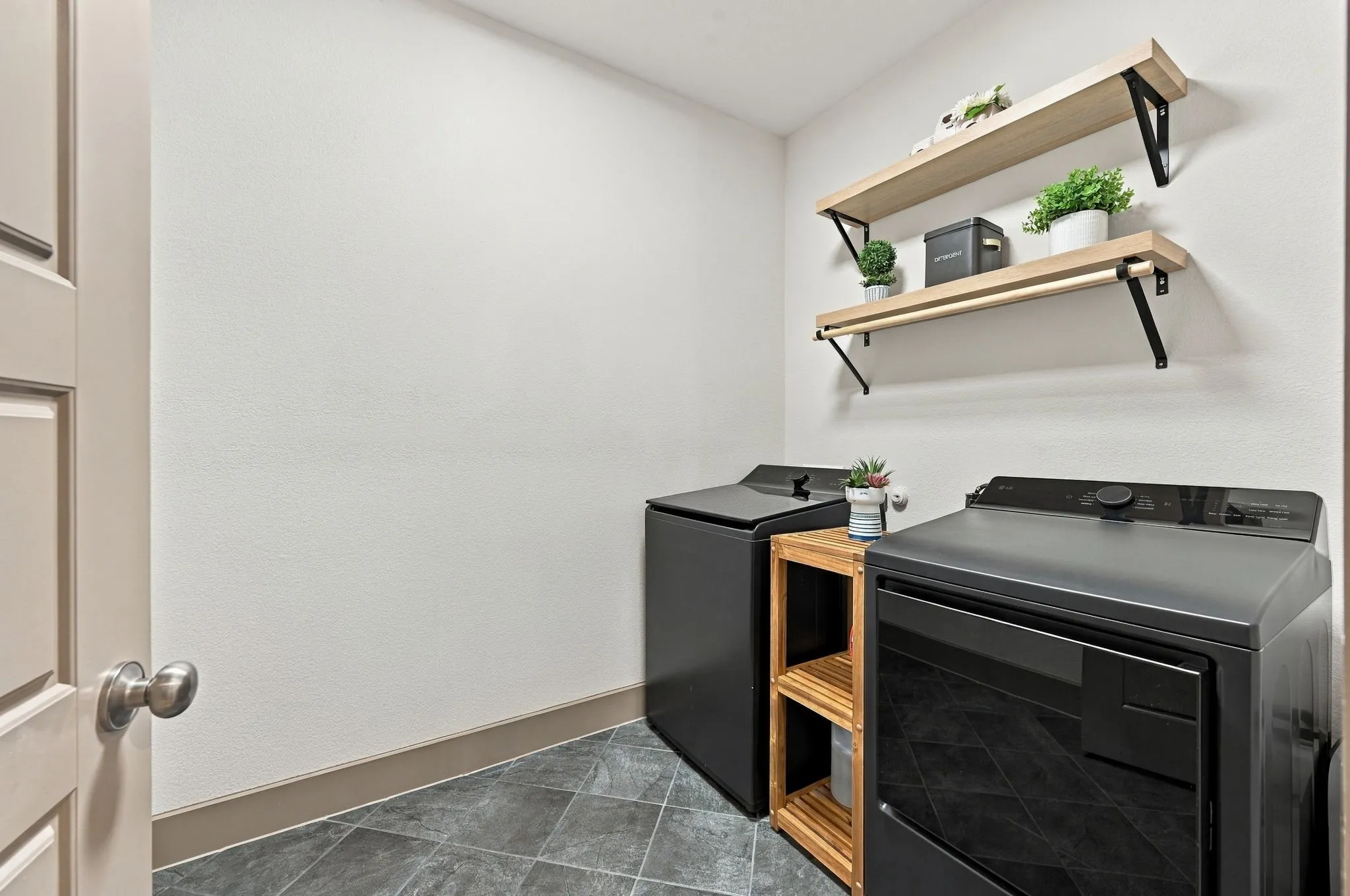 Tiled flooring, two wooden floating shelves with black brackets, and a built-in wooden shelving unit