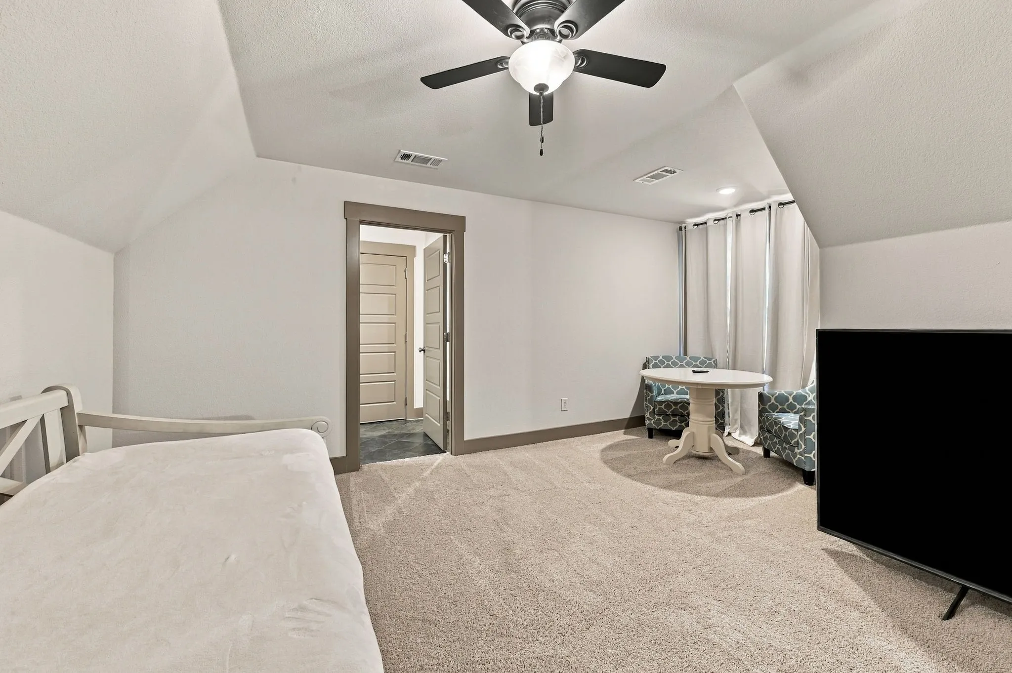 Sloped ceiling lines, neutral-toned carpet flooring, recessed lighting, and a ceiling fan with light fixture