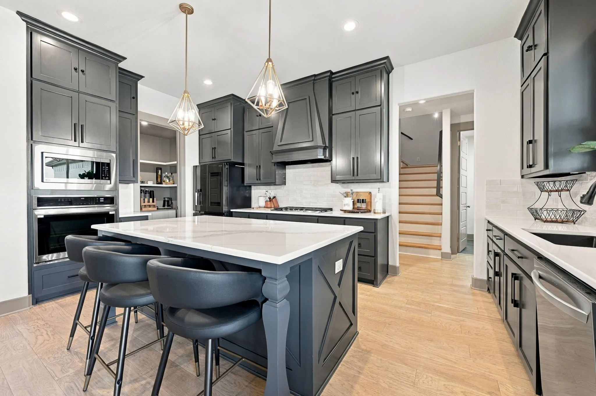 Kitchen featuring dark cabinetry, stainless steel appliances, a center island with a white countertop, and wood-finish flooring
