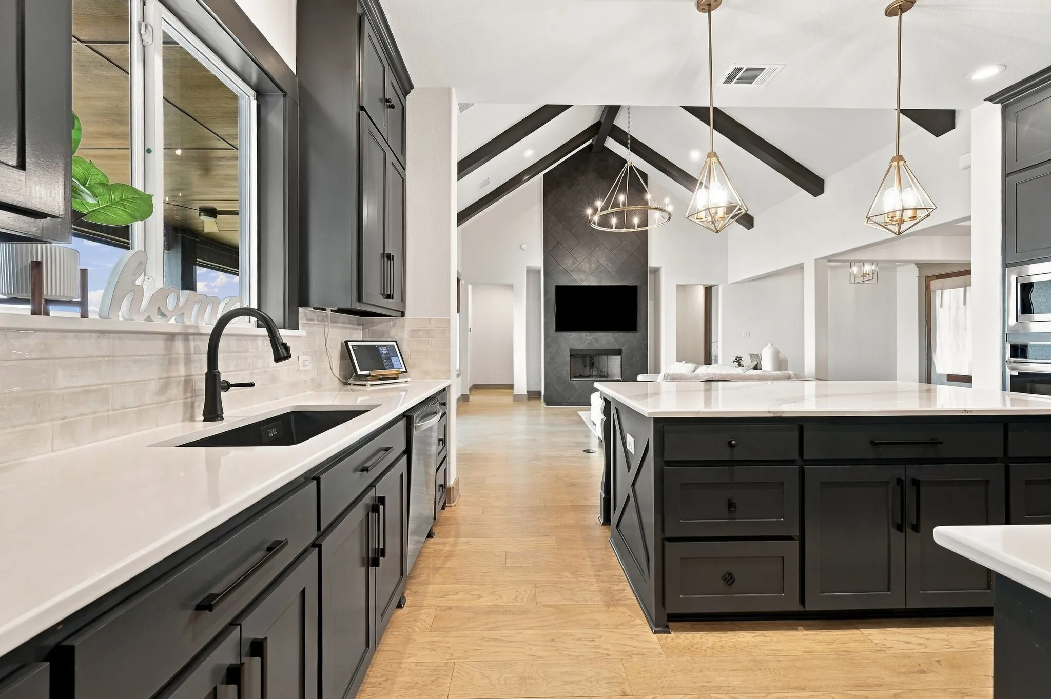Kitchen featuring a large central island with white countertops, dark cabinetry, wood-finish flooring, and pendant lighting