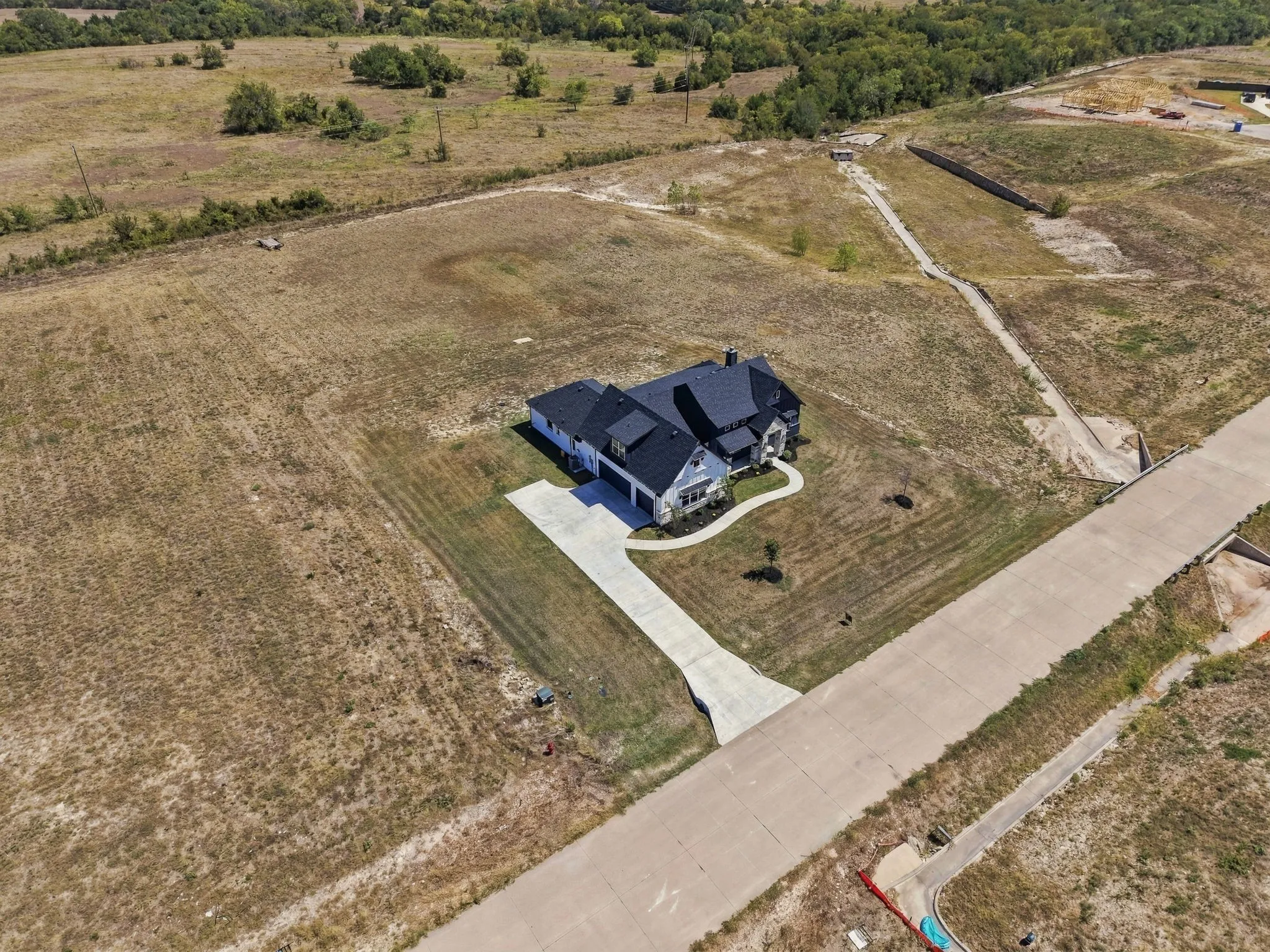 Expansive lot featuring a newly constructed residence, a paved driveway, and a concrete street