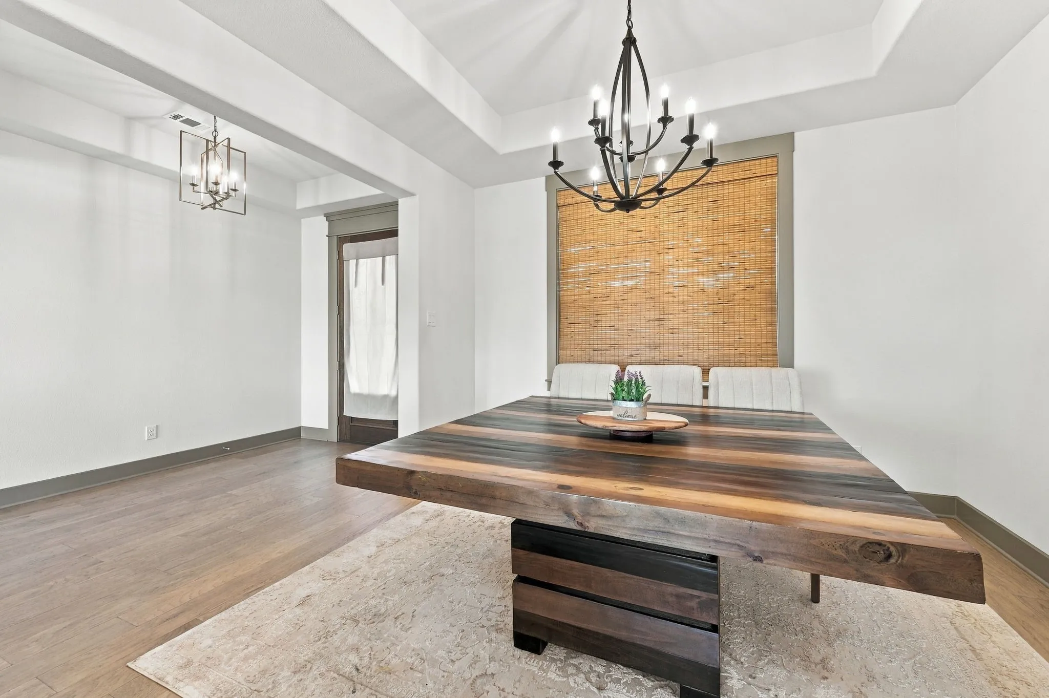 Tray ceiling with recessed lighting, wood-finish flooring, and a wrought iron chandelier