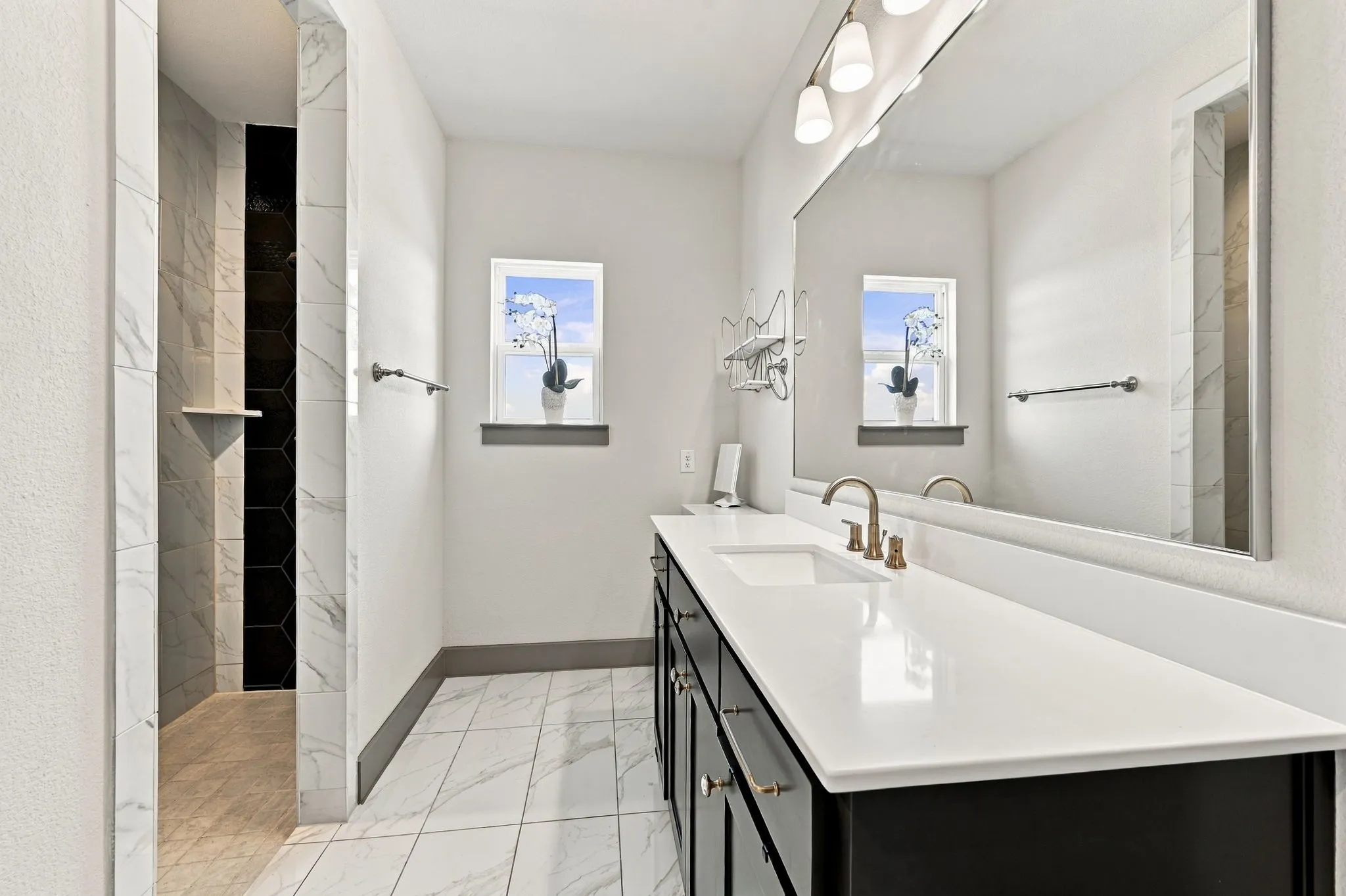 Spacious vanity with a wide basin, bronze-finish faucet, and an expansive mirror