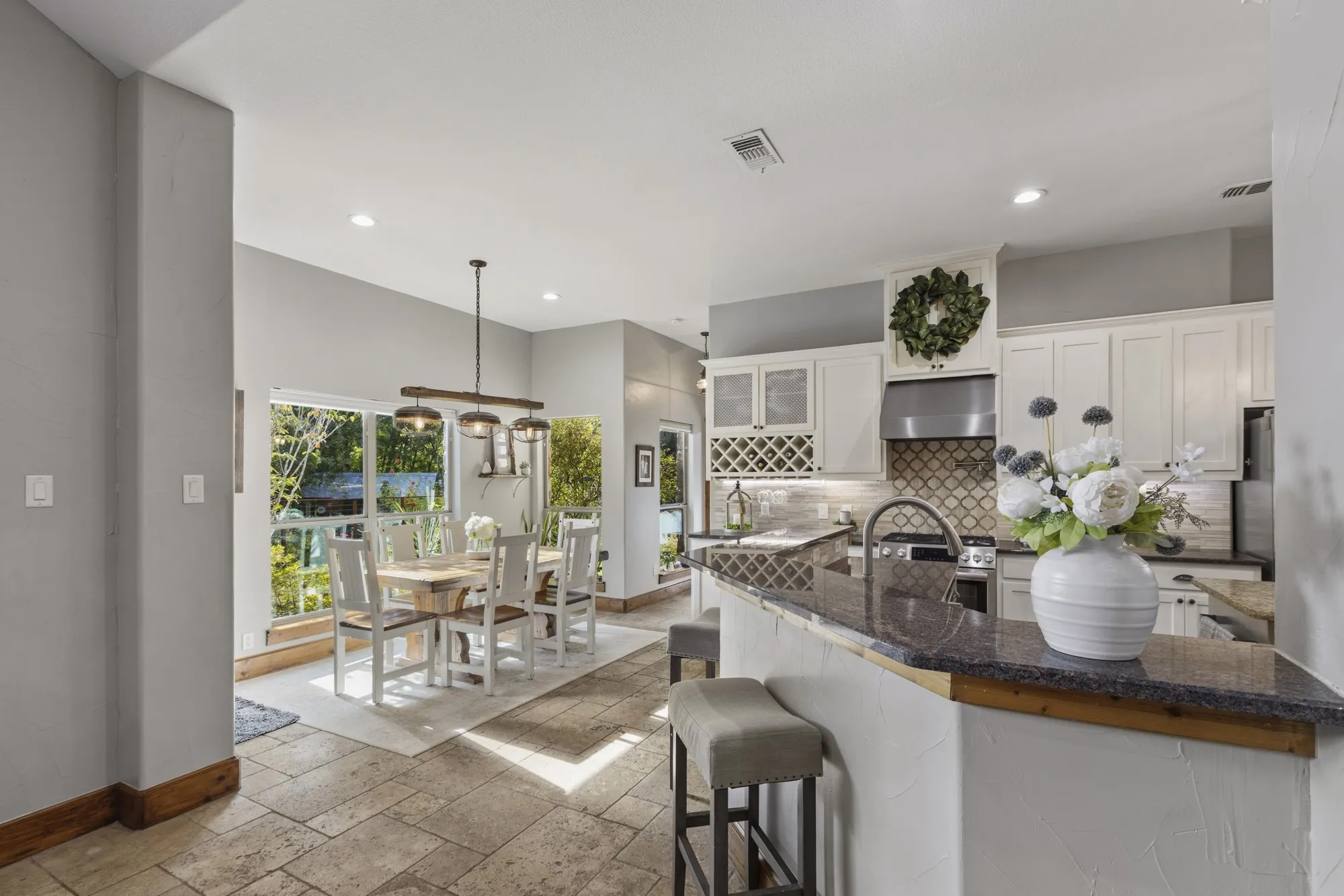 Kitchen featuring white cabinetry, stone countertops, a tile backsplash, and stainless steel appliances