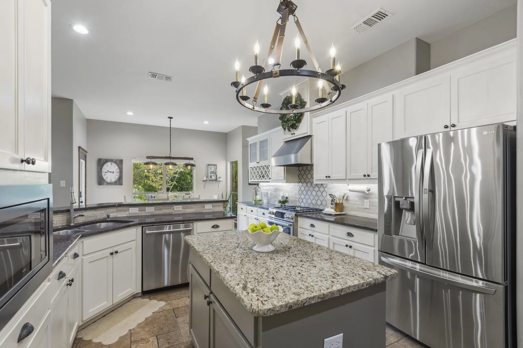 Spacious kitchen featuring an island, stainless steel appliances, white cabinetry, dark countertops, and tile flooring