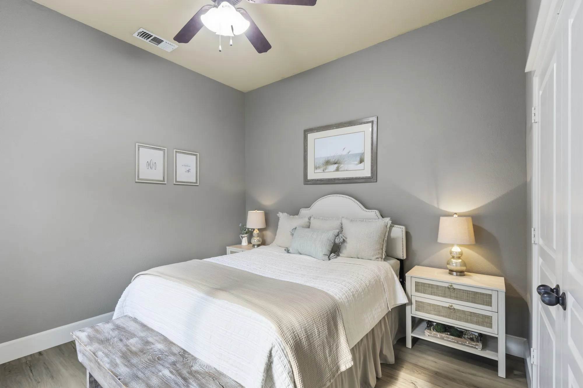 Wood-finish flooring, ceiling fan with integrated lighting, door with panel detailing, and a neutral color palette